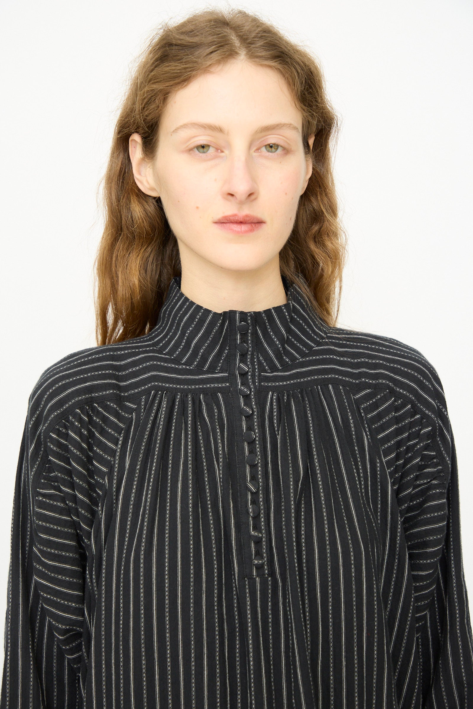 A person with long, wavy brown hair wears the Shirring Brushed Stripe Dress in Black by Ichi Antiquités, featuring white vertical stripes, against a plain white background.
