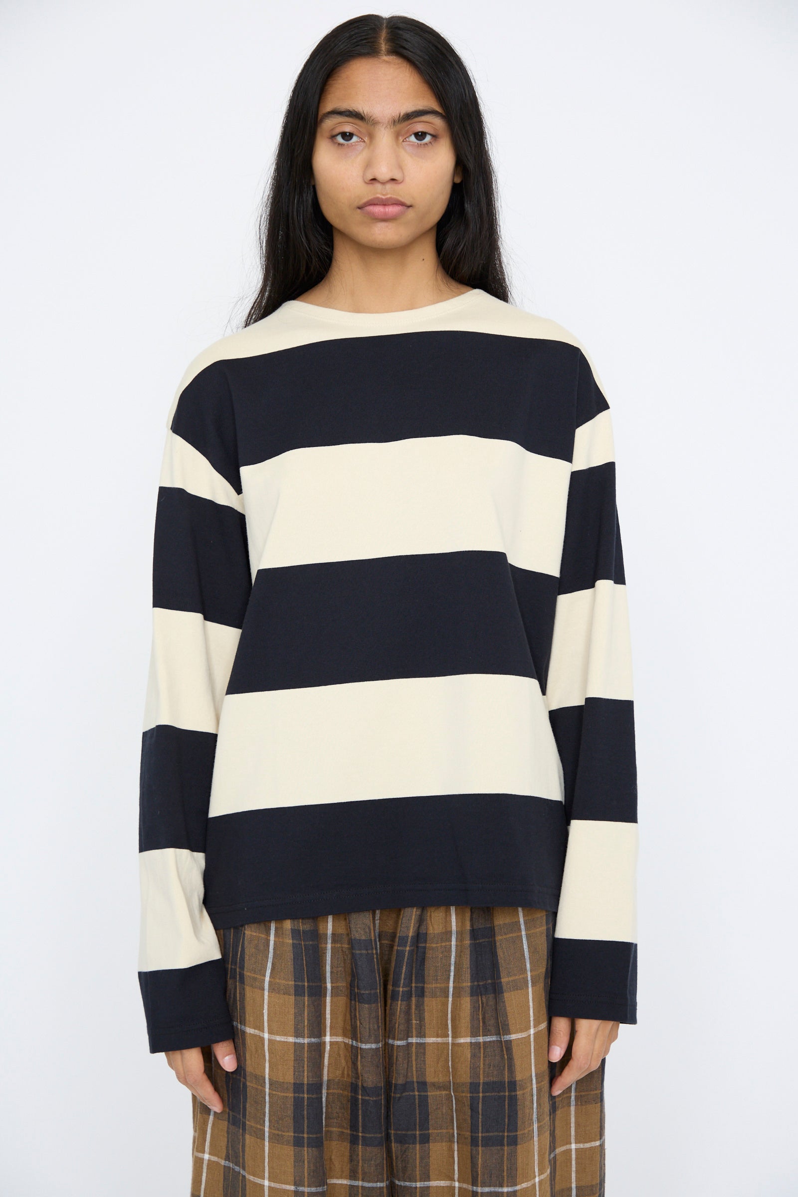 Someone wearing the Striped Crewneck in Beige and Black from Ichi Antiquités stands against a plain background.