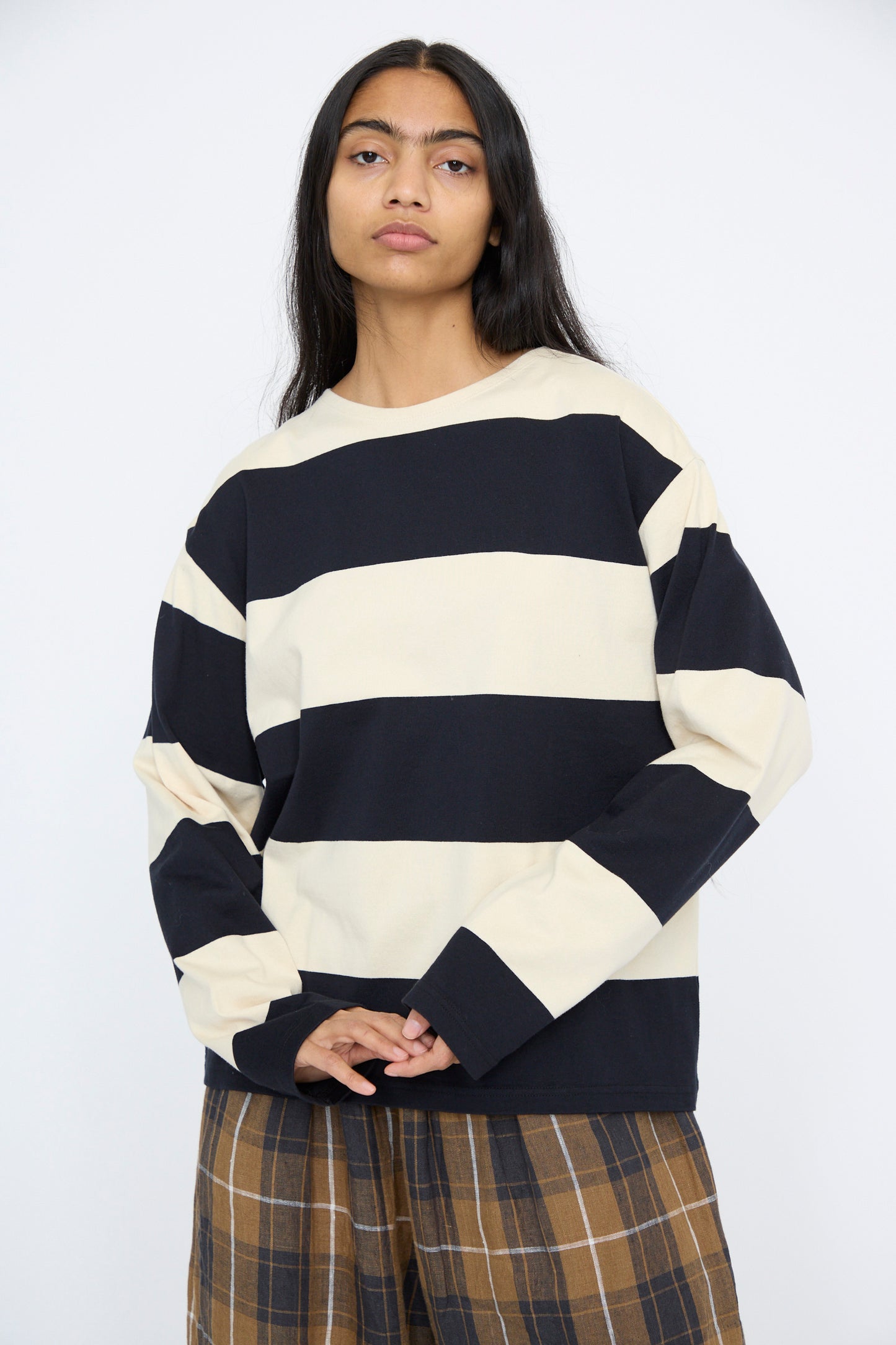 A person wearing Ichi Antiquités' Striped Crewneck in Beige and Black with brown plaid pants stands against a white background.