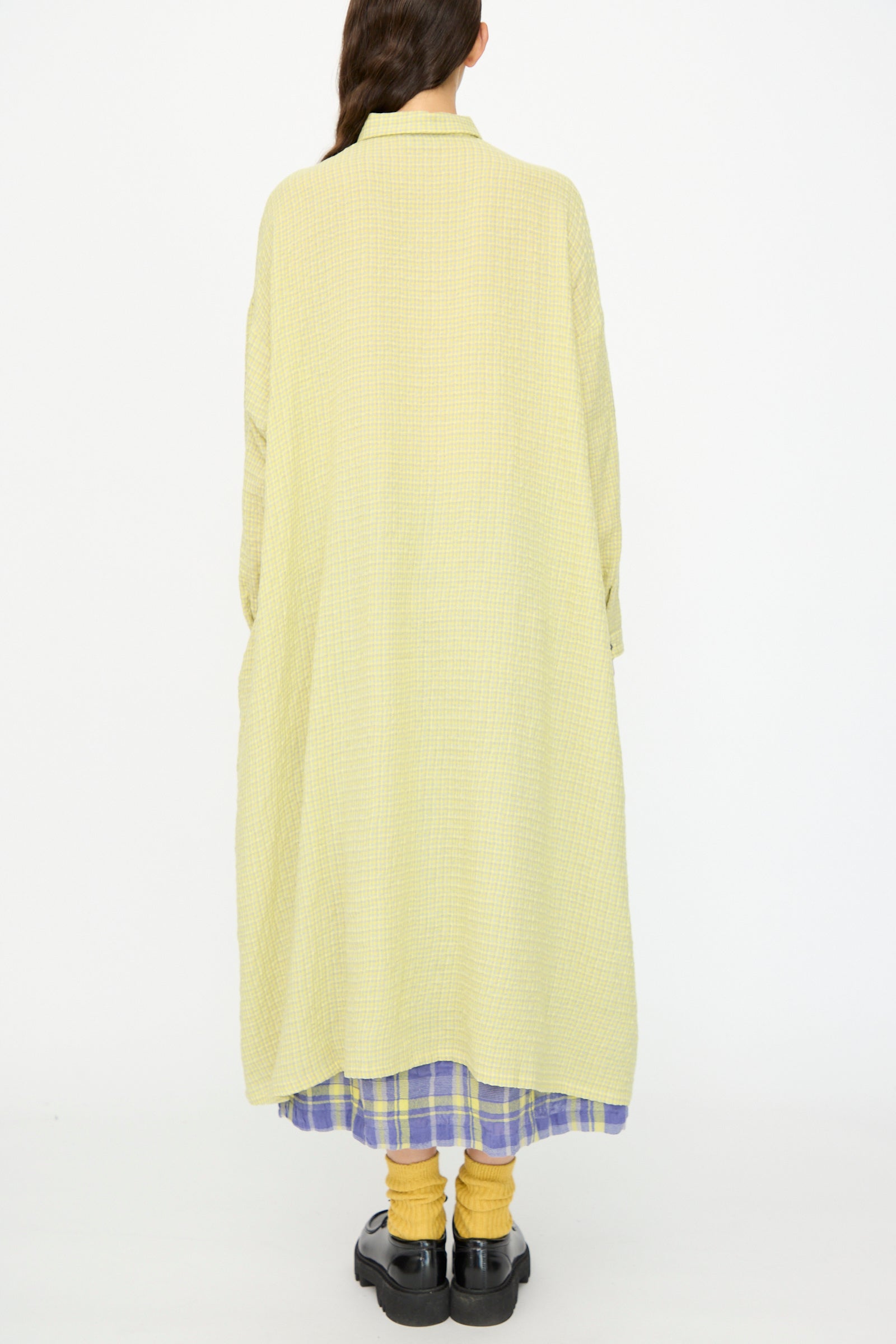 A person stands with their back to the camera, wearing the Ichi Antiquités Wool Cotton Gingham Dress in Yellow and Gray.