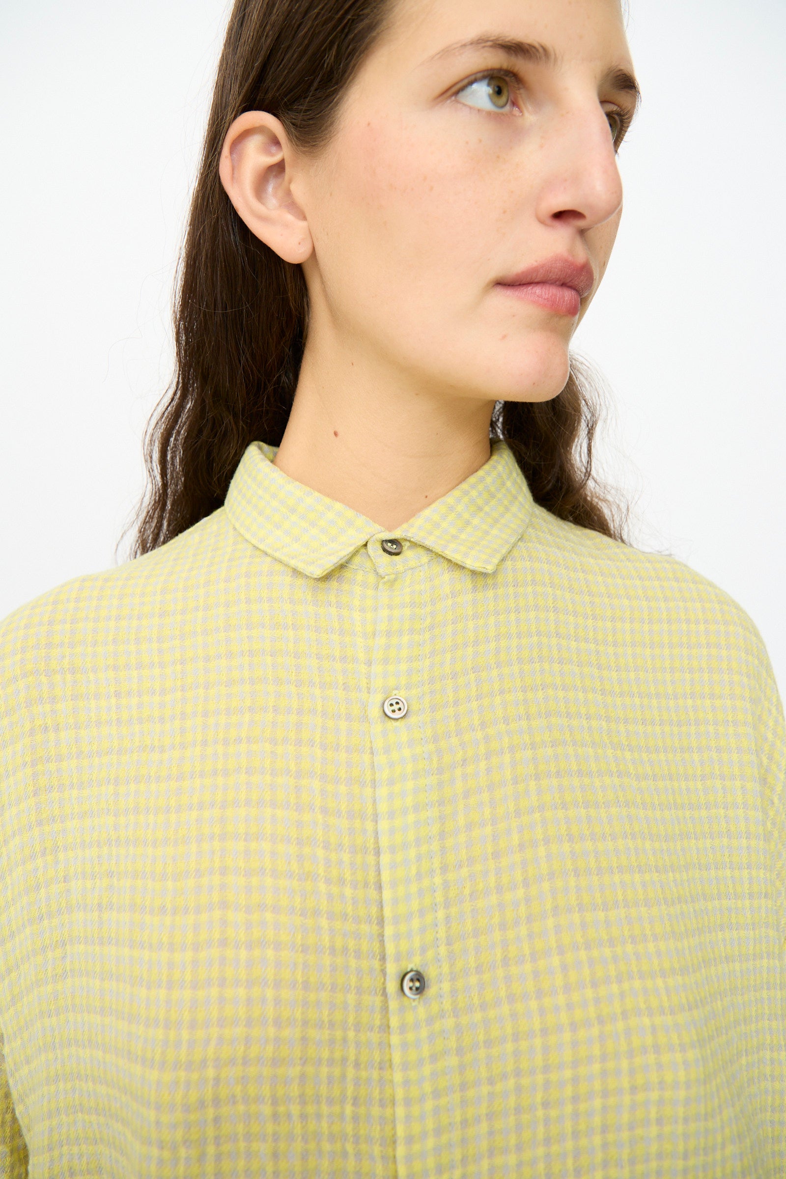 A person with long brown hair wearing the Ichi Antiquités Wool Cotton Gingham Dress in yellow and gray, looking to the side against a plain background.