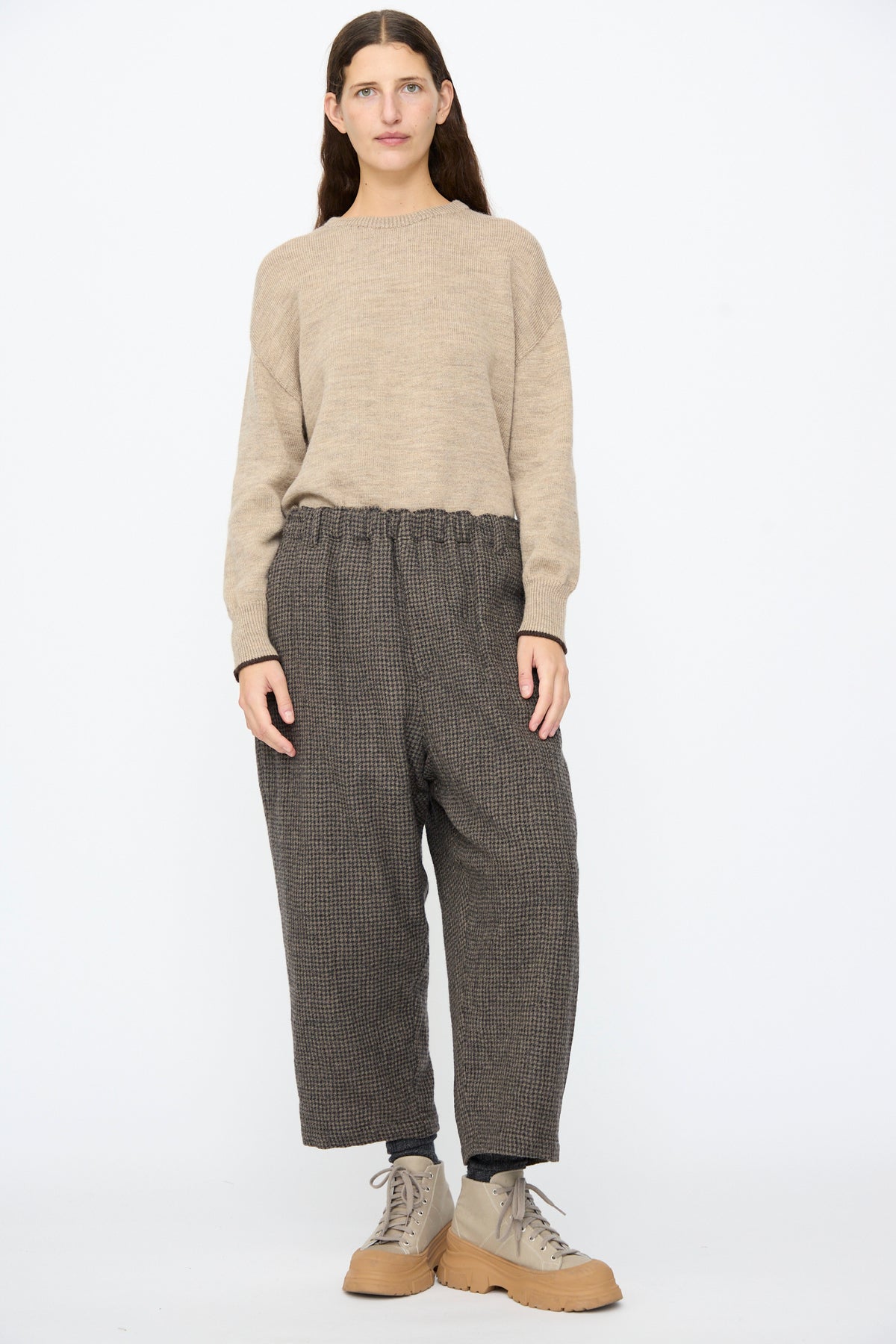 A woman wears a beige sweater and Ichi Antiquités Wool Gauze Houndstooth Pants in Mocha with a drawstring waist, paired with beige platform lace-up boots.
