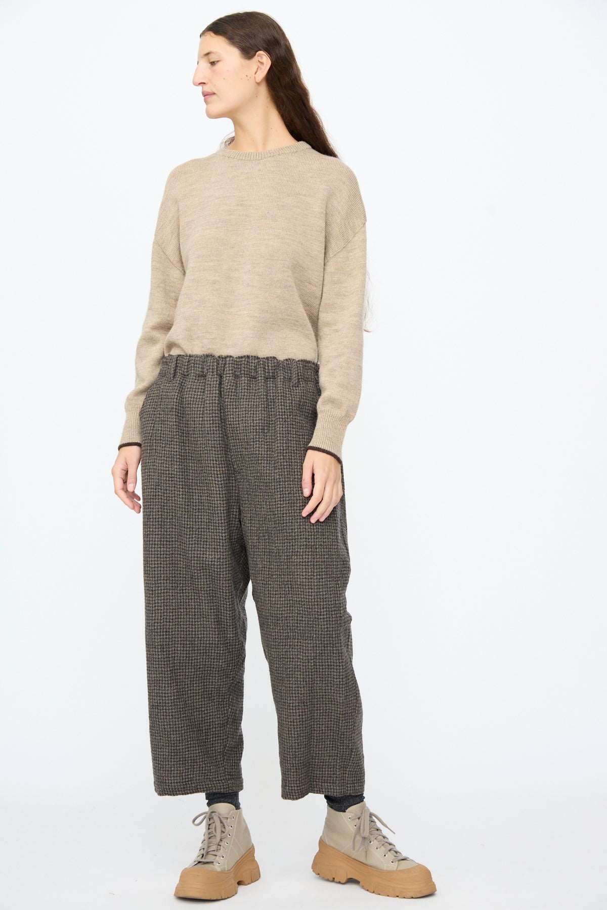 Person wearing a tan crewneck sweater and Ichi Antiquités Wool Gauze Houndstooth Pants in Mocha with an elastic waistband, paired with beige lace-up boots.