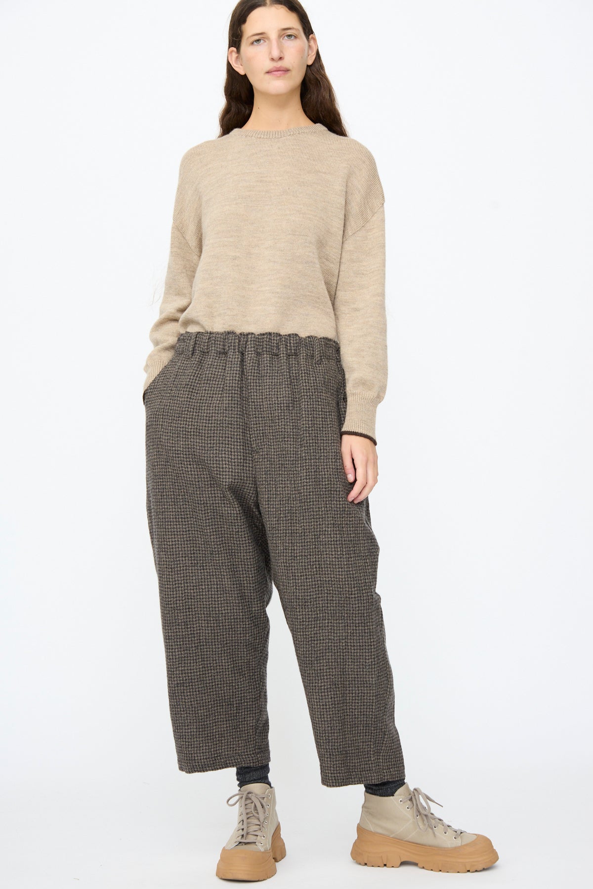 A person wearing a beige sweater, Ichi Antiquités Wool Gauze Houndstooth Pants in Mocha, and beige lace-up boots with chunky soles.
