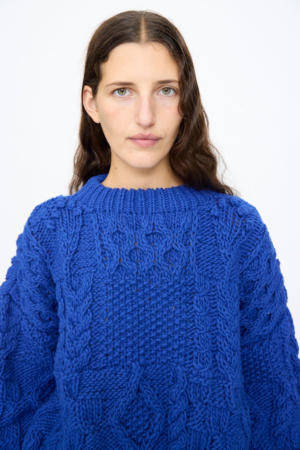 A person wearing an oversized, royal blue Ichi Antiquités Wool Hand Knit Pullover with a cable-knit texture and crew neckline.