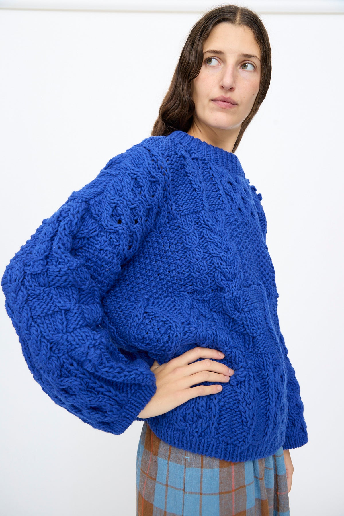 A person wearing an oversized, cobalt blue Ichi Antiquités Wool Hand Knit Pullover featuring a chunky cable knit.