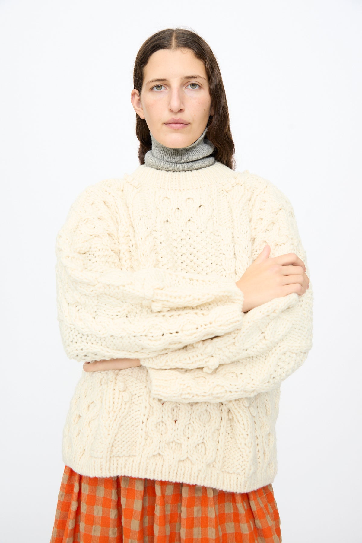 Person wearing an Ichi Antiquités Wool Hand Knit Pullover in White over a grey turtleneck and an orange and beige checkered skirt.