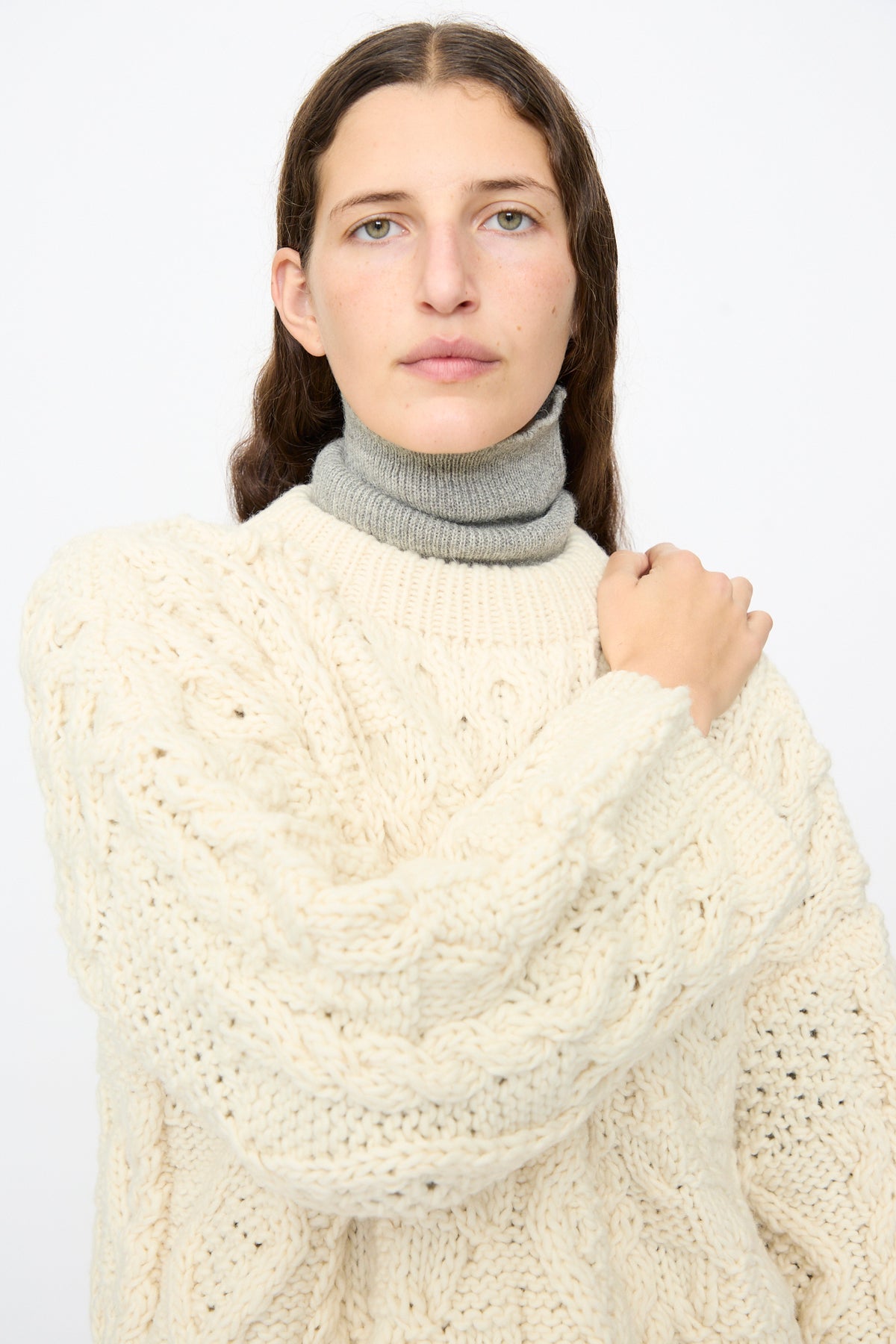 An oversized Ichi Antiquités Wool Hand Knit Pullover in White is layered over a grey turtleneck.