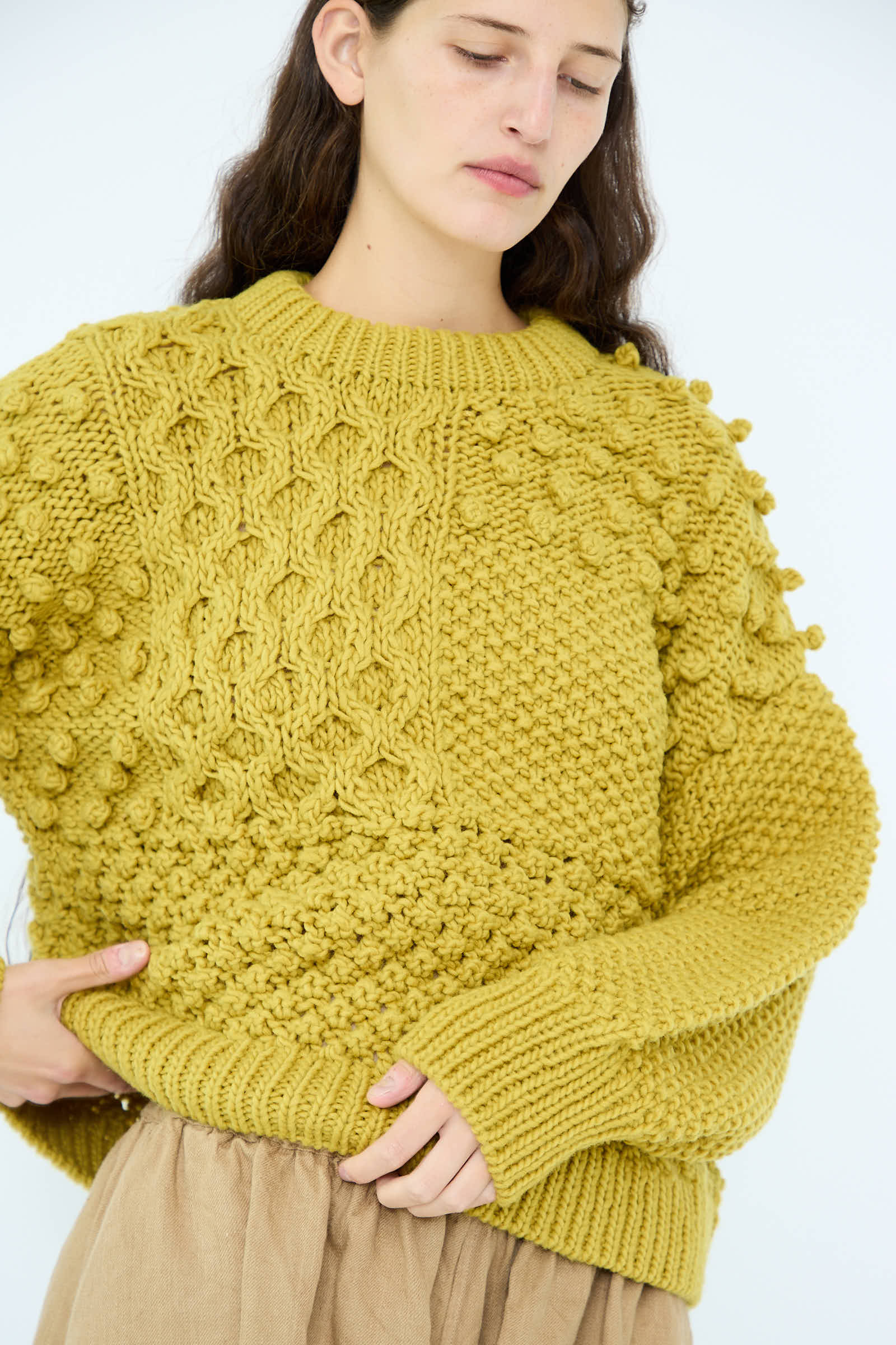 A person with long dark hair wears the Wool Hand Knit Pullover in Yellow, made from 100% wool by Ichi Antiquités, paired with a beige skirt against a plain background.