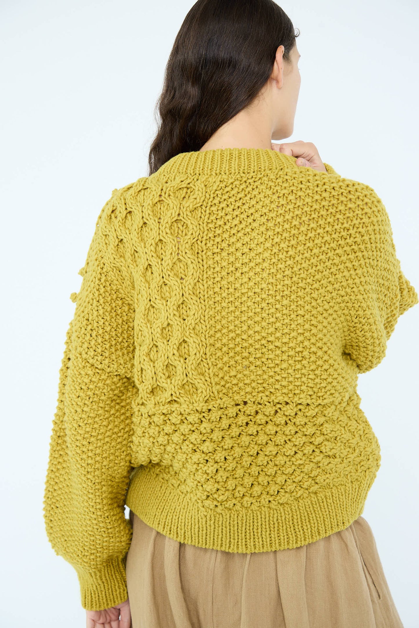 An individual is wearing the Wool Hand Knit Pullover in Yellow by Ichi Antiquités, featuring textured patterns, and is standing against a plain background.