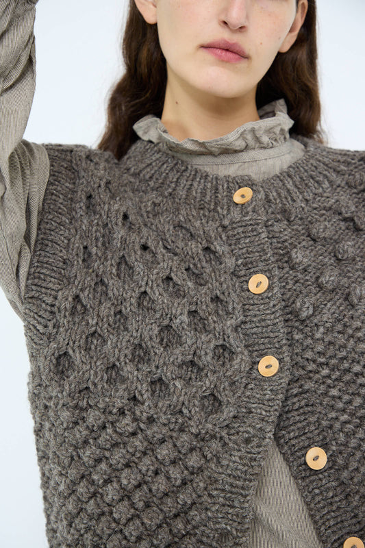 A person wearing the Ichi Antiquités Hand Knit Wool Vest in Mocha over a ruffled blouse showcases the charm of hand-knit detailing.