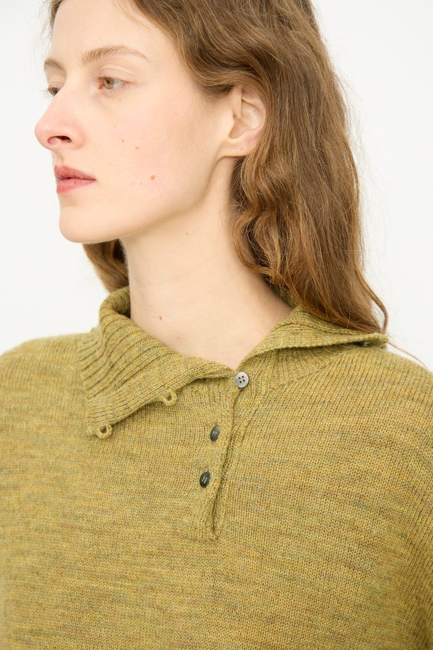 A woman with long brown hair wears the Ichi Antiquités Wool Whole Garment Knit Pullover in mustard, looking to the left against a plain background.