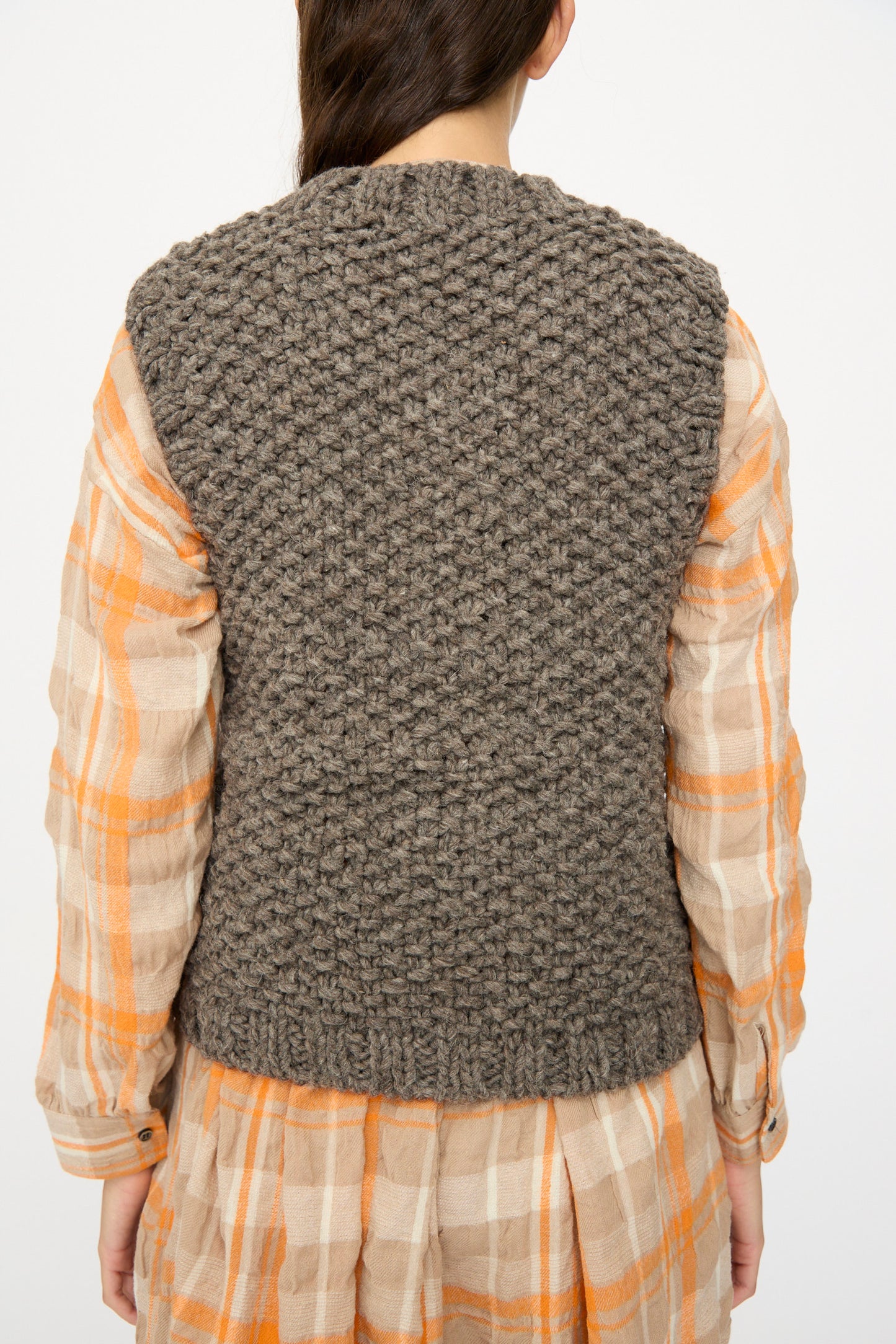 A person wears the Ichi Antiquités Wool Peru Hand-knit Vest in Gray over an orange and beige plaid dress, photographed from the back.