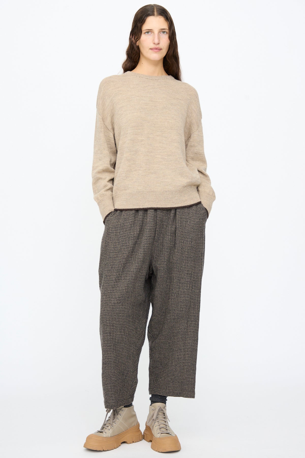 A person wearing an Ichi Antiquités Wool Pullover in Beige and Brown, loose brown patterned trousers, and beige platform sneakers.