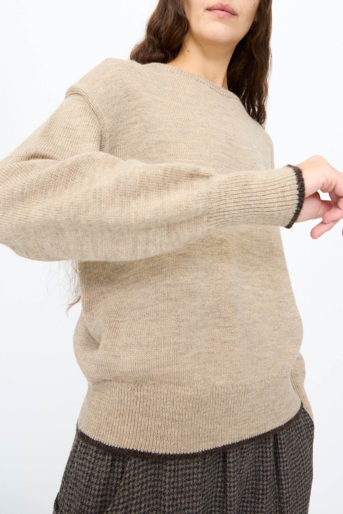 Ichi Antiquités Wool Pullover in Beige and Brown, a crewneck with brown trim on the cuffs and hem, worn with brown patterned trousers.