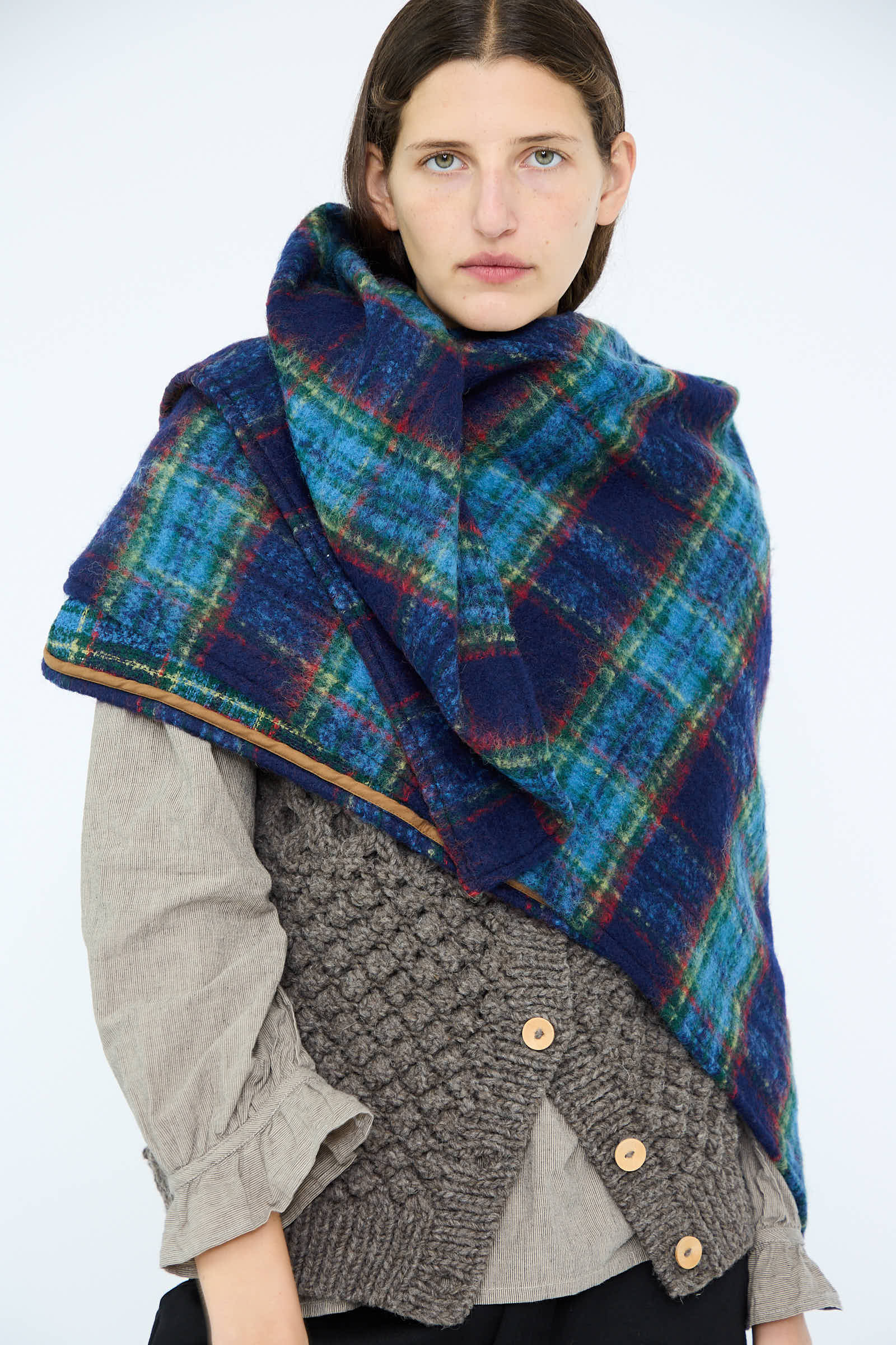 Clad in the Wool Tartan Shaggy Stole in Navy by Ichi Antiquités, a person elegantly drapes it over their gray textured sweater.