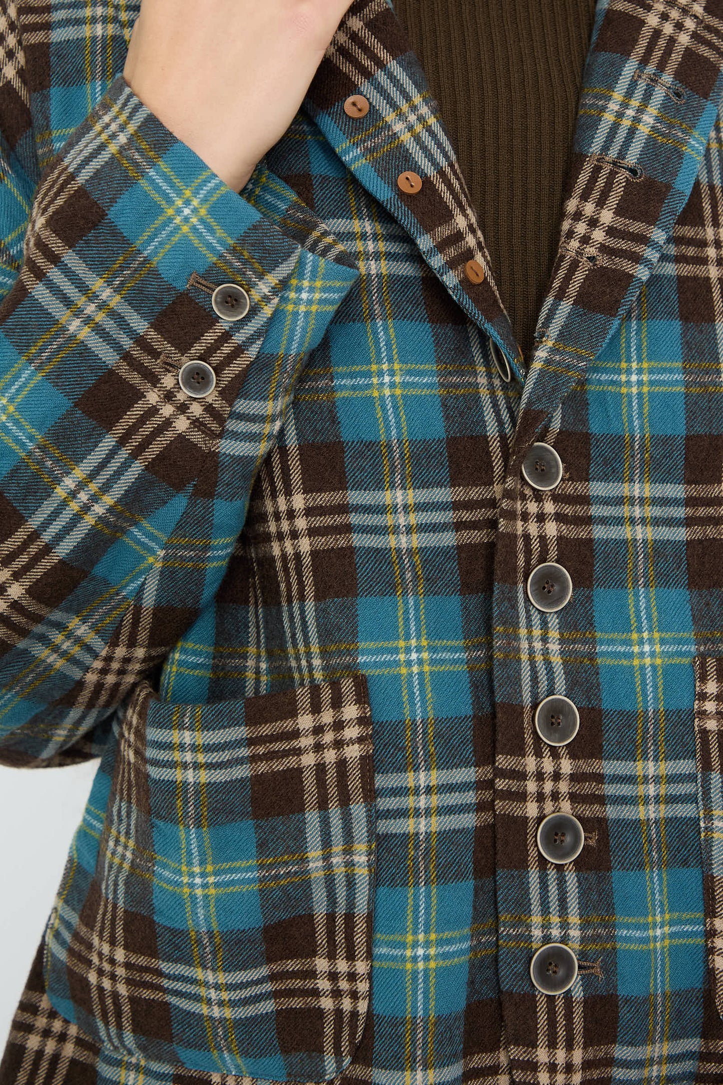 A close-up of a person wearing the Ichi Antiquités Wool Washer Tartan Jacket in Blue, featuring a relaxed fit and blue and brown plaid pattern over a brown top.