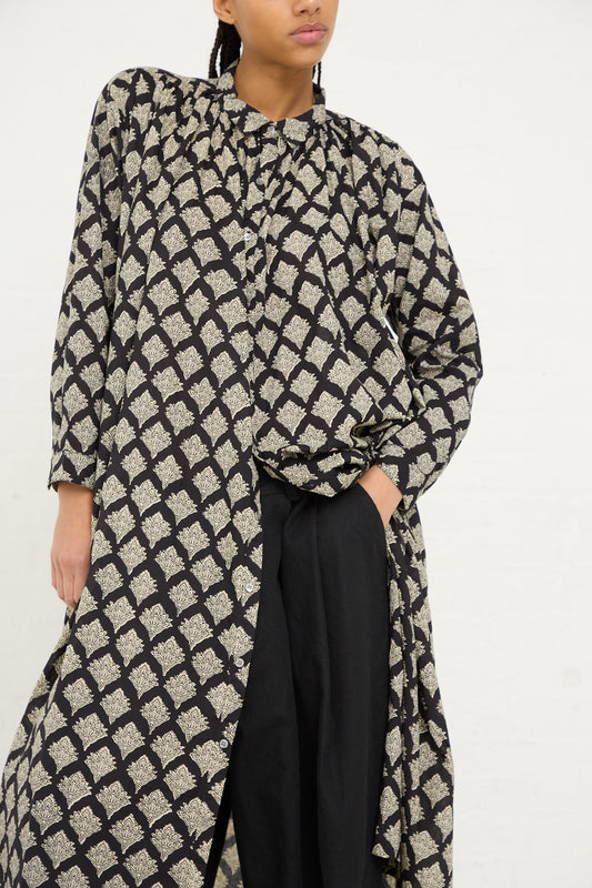 A person wearing an Ichi Antiquités Woven Cotton Indian Block Print Dress in Black over black trousers.