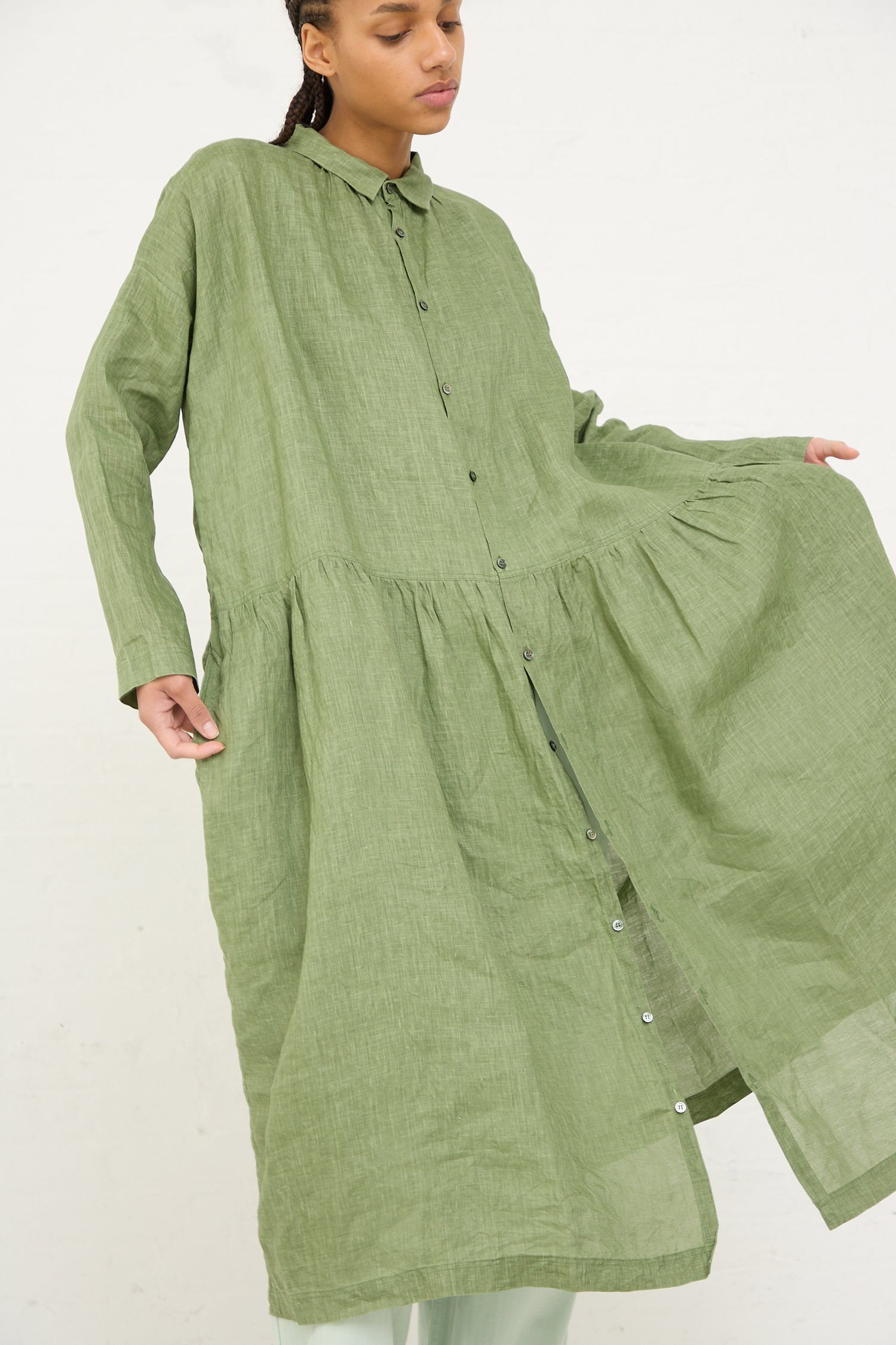 Woman in an oversized Ichi Antiquités Woven Linen Dress in Green with buttons standing against a white background.