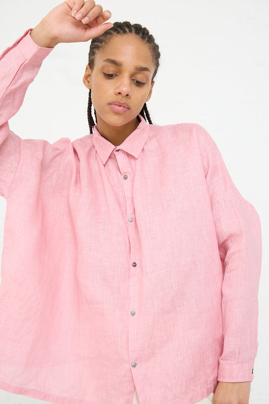 A person in an Ichi Antiquités woven linen shirt in pink pigment dyed color with braided hair looking downward.