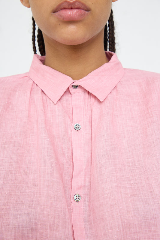 Close-up of a person wearing a pink pigment-dyed, Woven Linen Shirt with a collar from Ichi Antiquités.