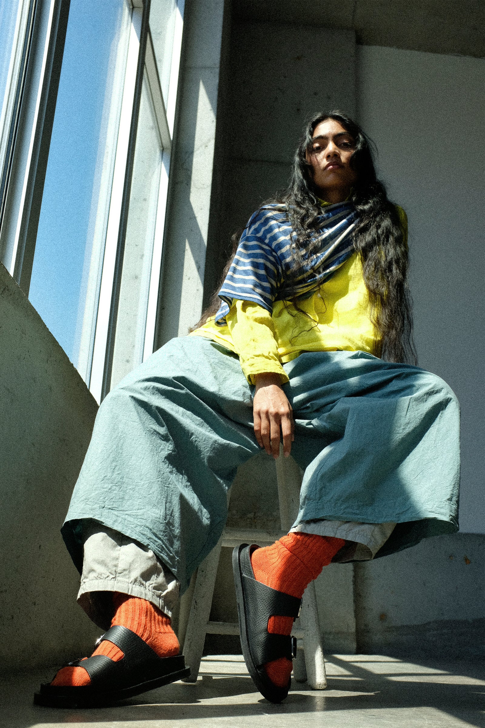 Person sitting on a stool next to a window wearing pieces from Ichi Antiquités PF26 collection.