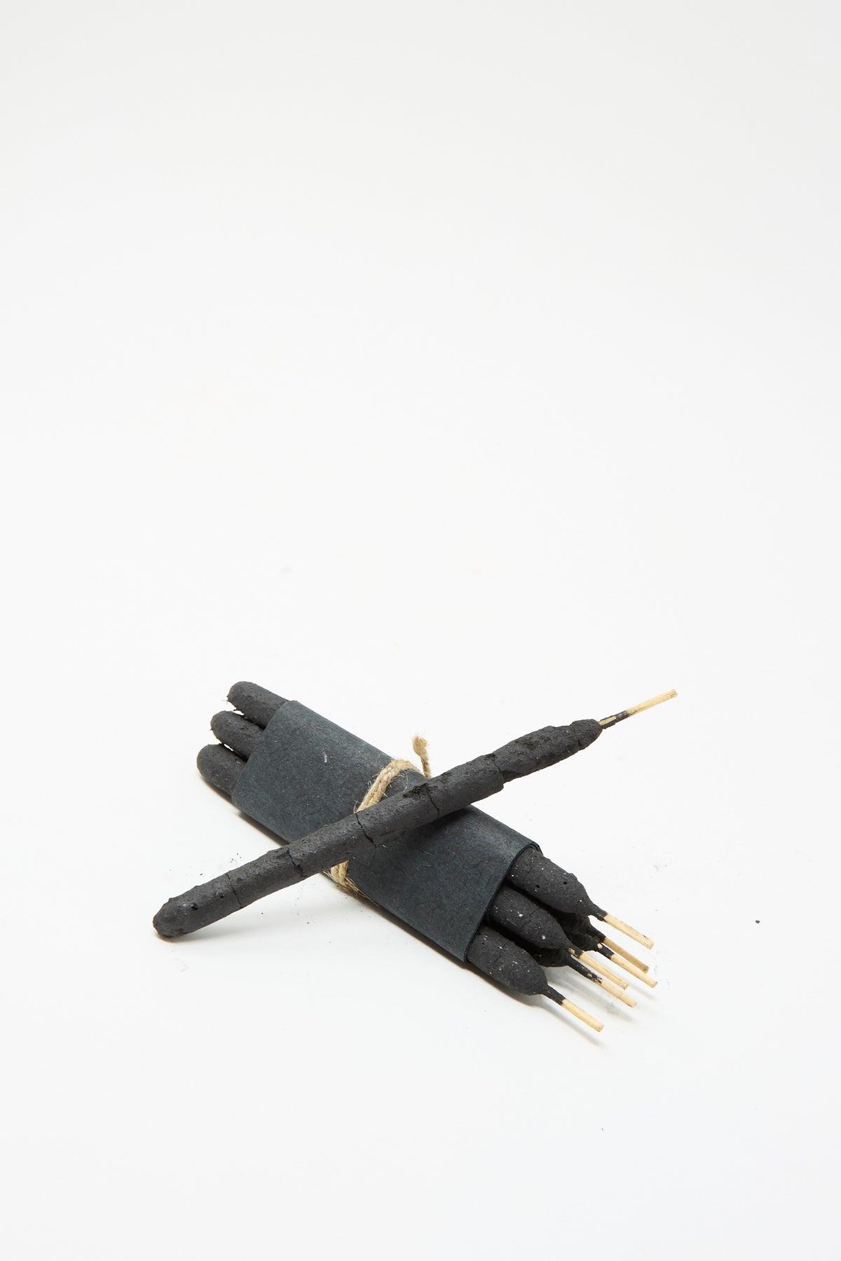 A bundle of six black Half Dozen Incense Bundles in Chacrona & Jacube incense sticks tied with twine, with one additional stick resting across the top.