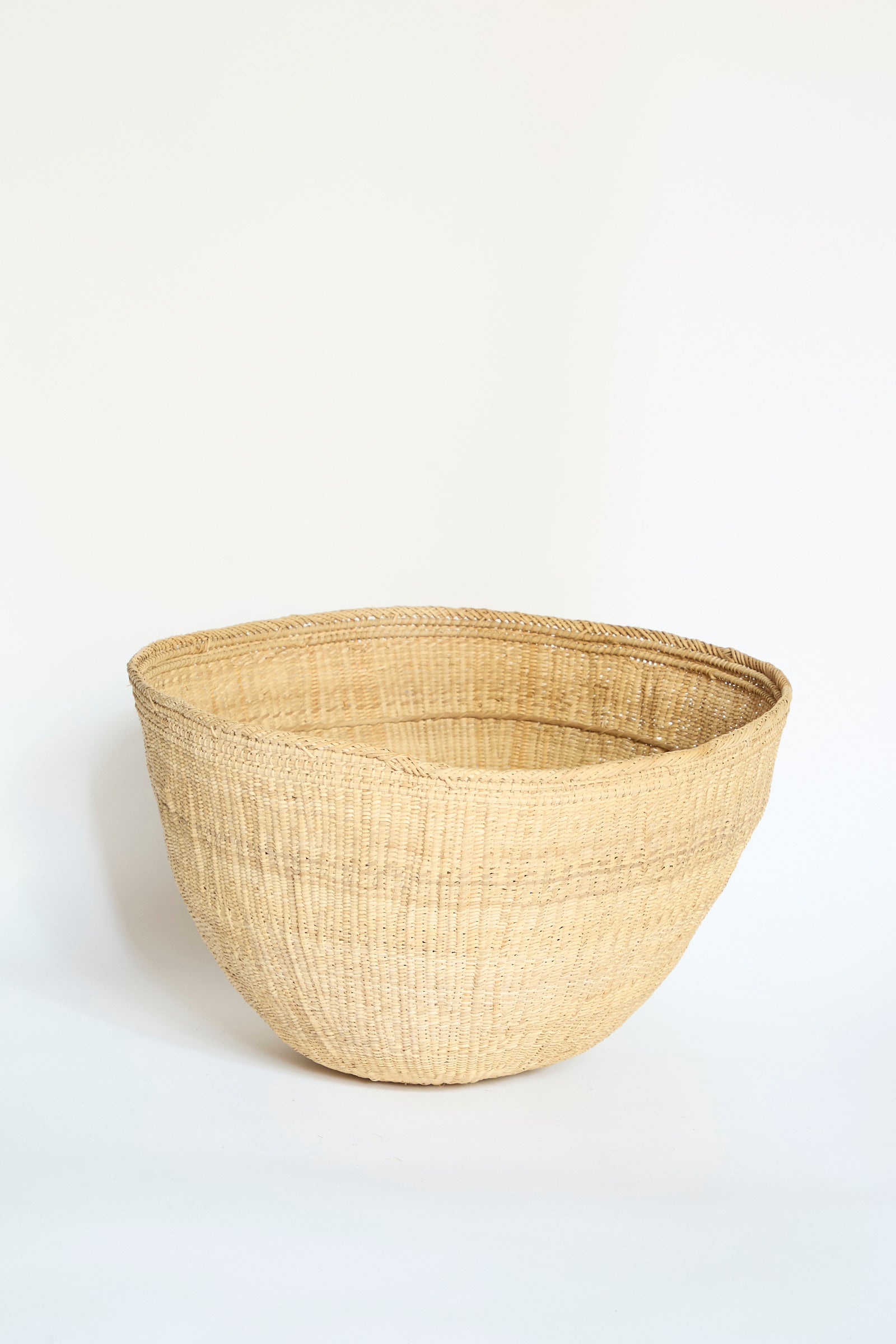 The Yanomami Wii Basket Large in Natural by Incausa is a spacious, handwoven basket featuring a rounded shape and crafted from natural materials, shown against a plain white background.