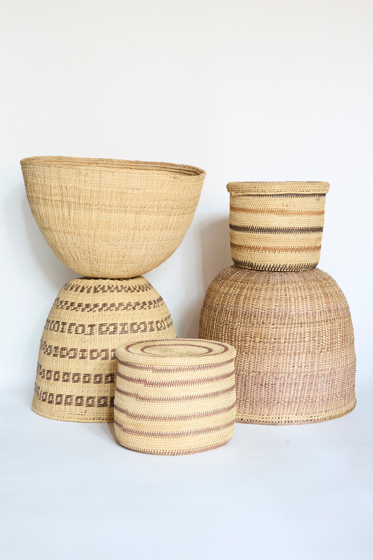 Four woven baskets of varying sizes and patterns, including the beautifully crafted Yanomami Wii Basket Large in Natural by Incausa, are displayed against a plain white background.