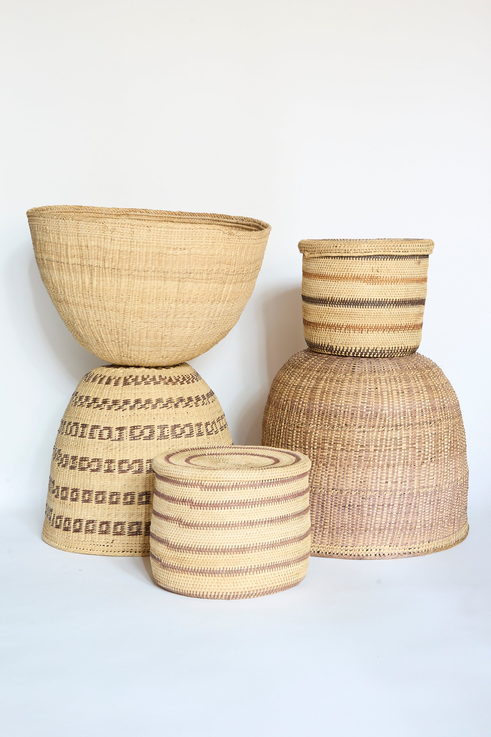 Four woven baskets of varying sizes and patterns, including the beautifully crafted Yanomami Wii Basket Large in Natural by Incausa, are displayed against a plain white background.