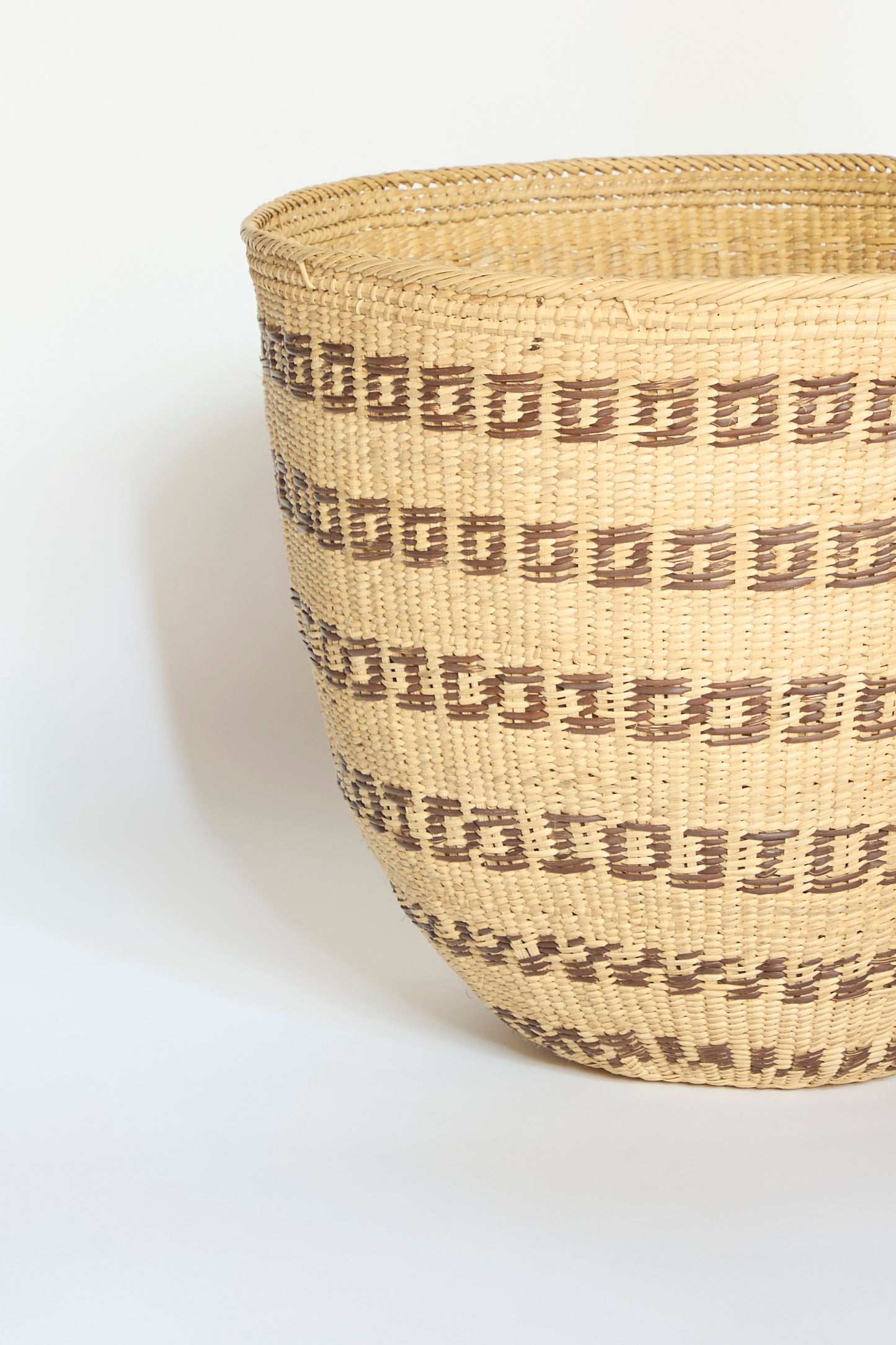 The Incausa Yanomami Wii Basket Large in Natural with Squares features a handwoven design crafted from durable Titica vine, showcasing a wide opening and tan color adorned with horizontal brown geometric square patterns. This storage basket by the Yanomami is photographed against a plain white background.