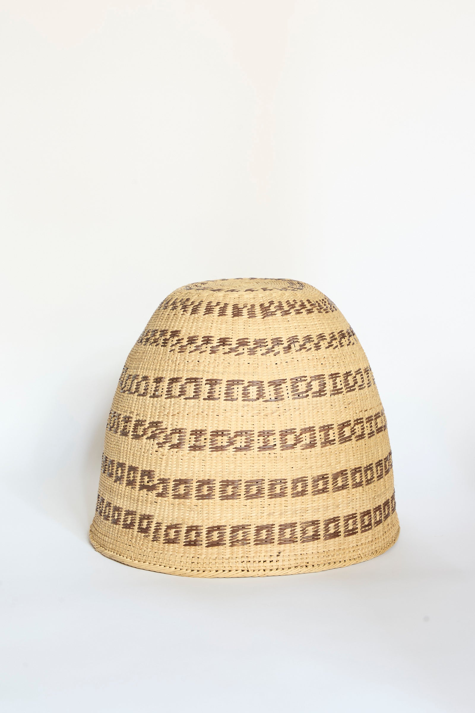 The Yanomami Wii Basket Large in Natural with Squares by Incausa features a rounded dome shape and geometric brown square patterns on a light natural background. Handwoven from resilient Titica vine, it is displayed against a plain white surface.