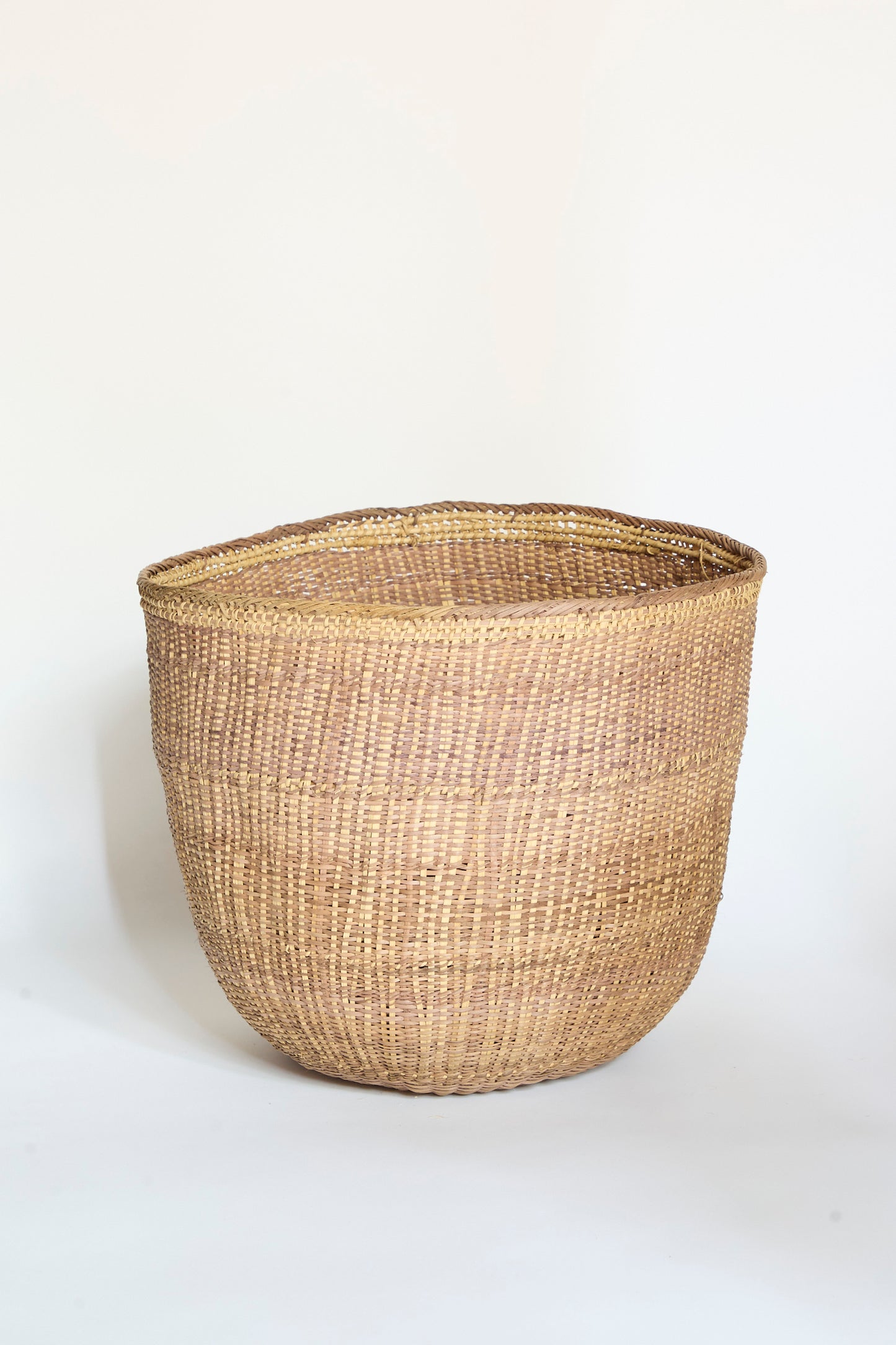 The Yanomami Wii Basket XL in Mixed Pigment by Incausa, a spacious round basket handwoven from natural fibers and Titica vine, is displayed on a plain white background.