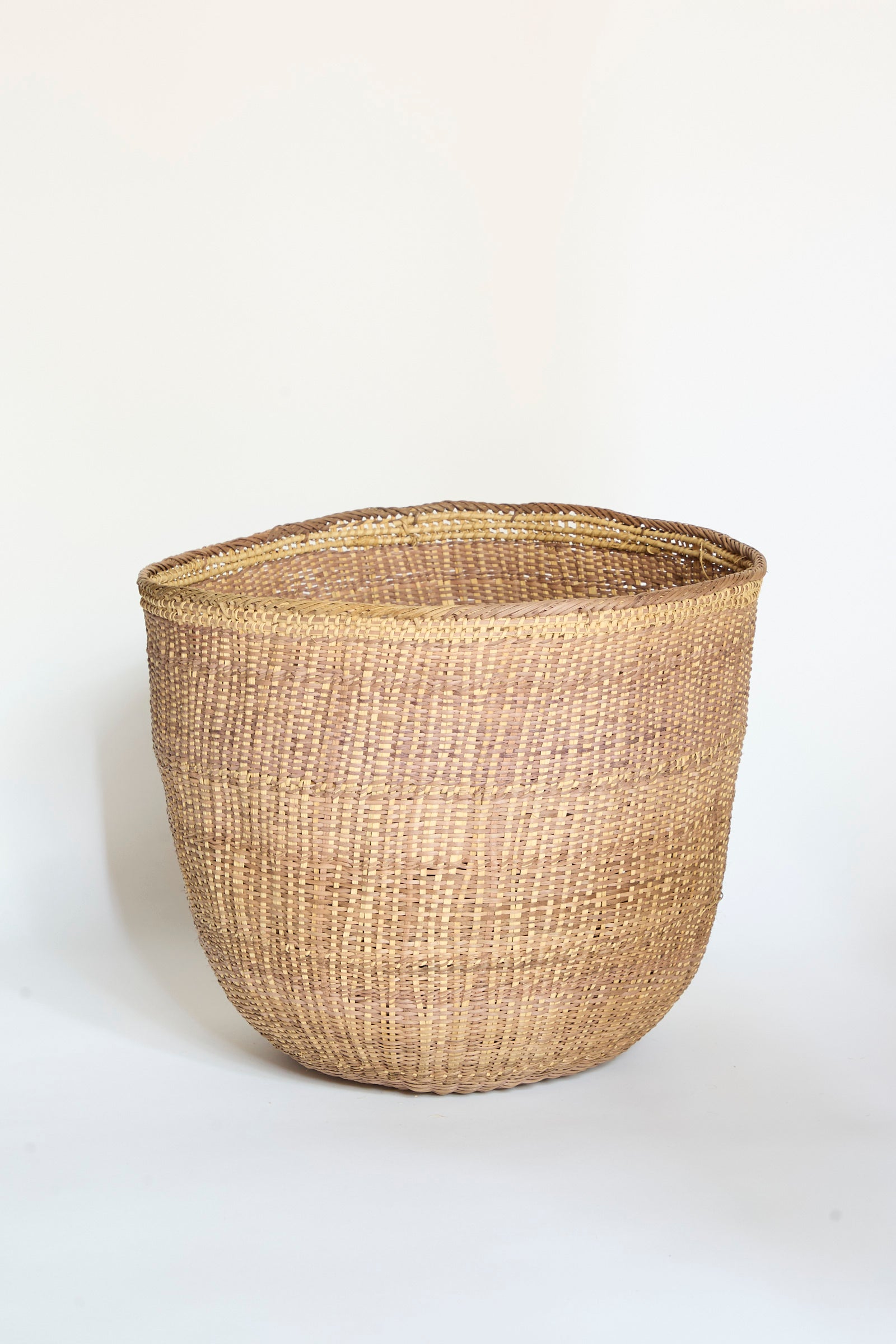 The Yanomami Wii Basket XL in Mixed Pigment by Incausa, a spacious round basket handwoven from natural fibers and Titica vine, is displayed on a plain white background.