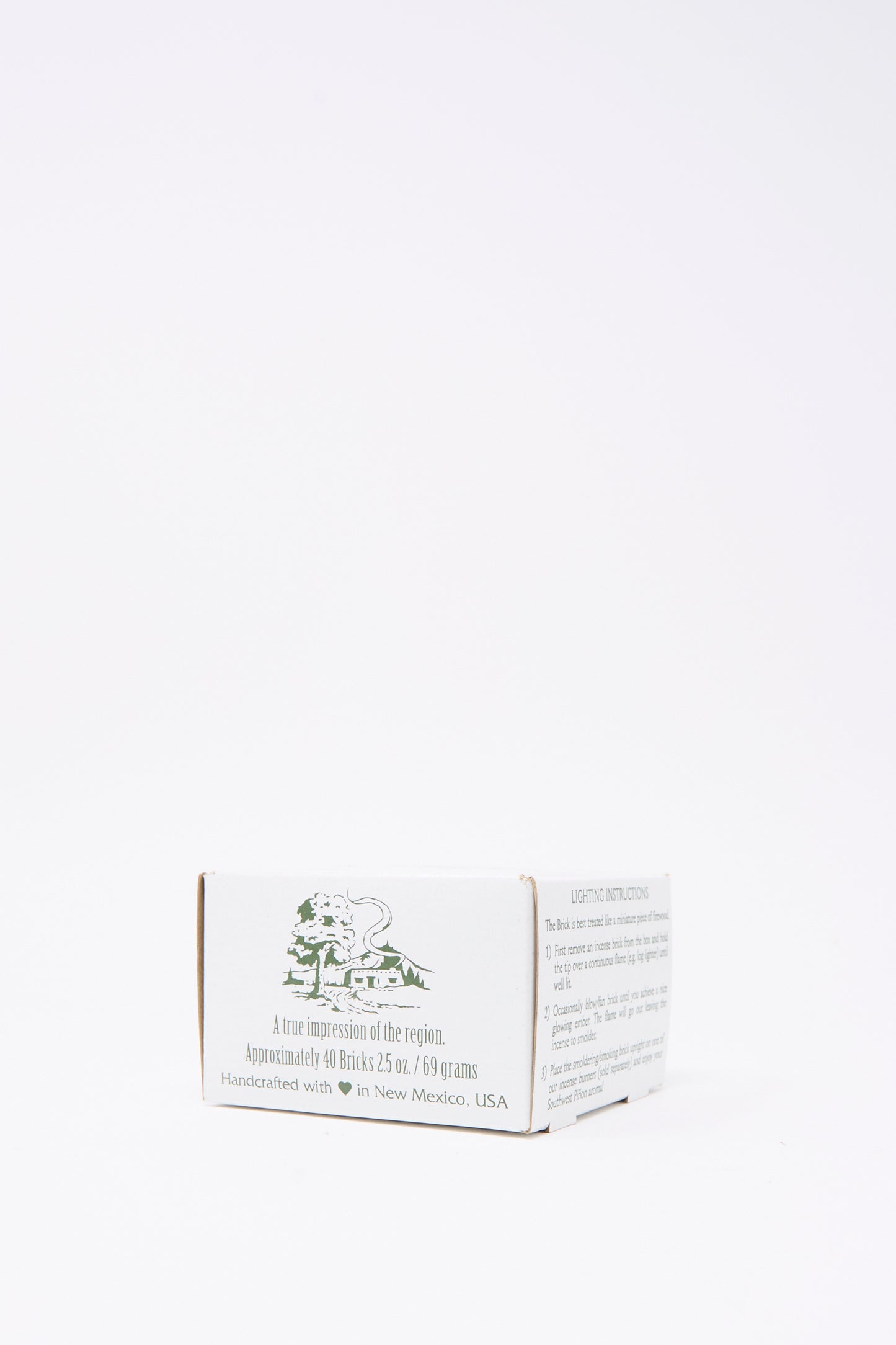 The Piñon Incense Box by Incense of the West features a small white box with green text and illustration, handcrafted in New Mexico—ideal for storing piñon pine incense or using with New Mexican clay burners.