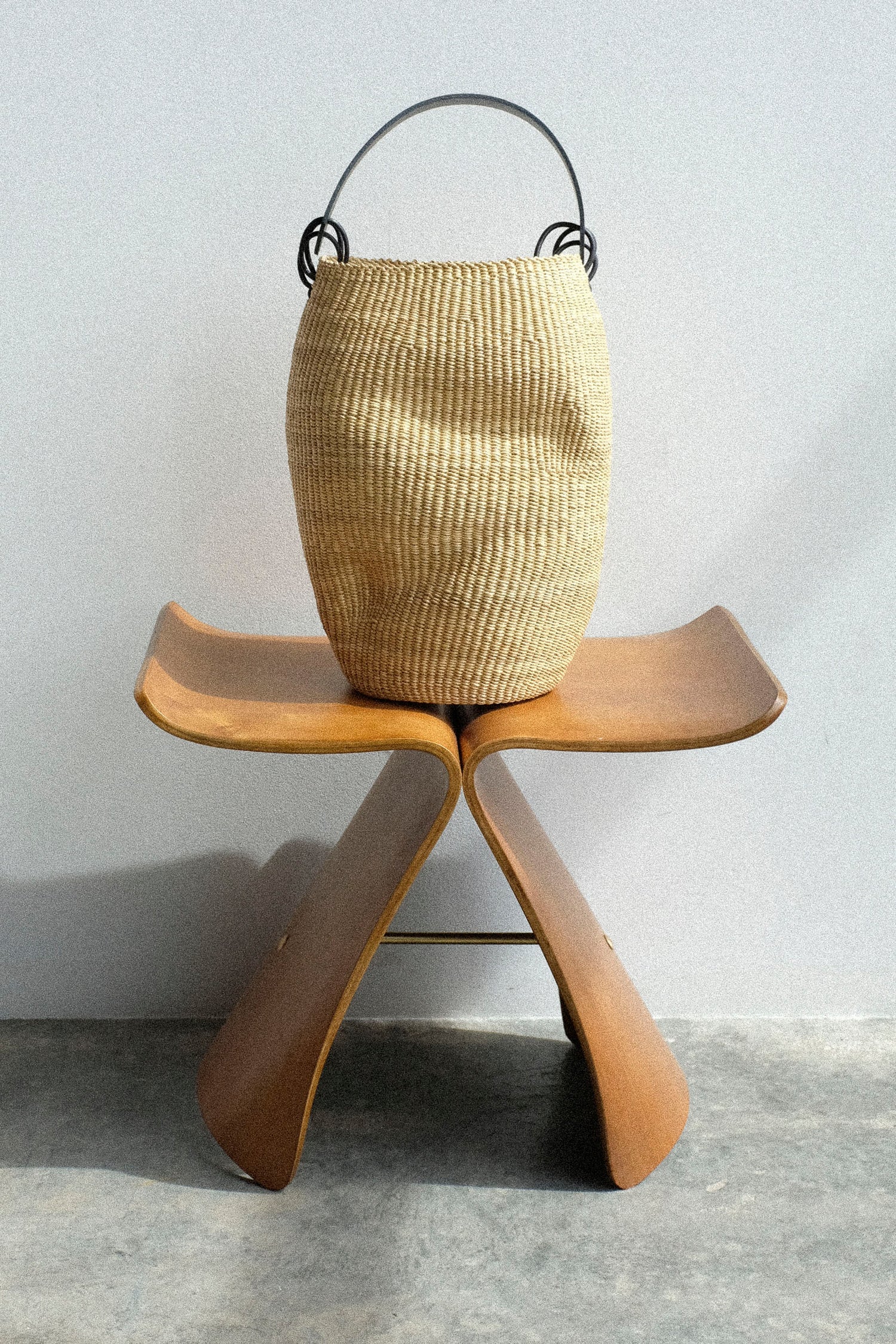 The Inès Bressand Pot Froissé Bag in Natural on a wooden stool.