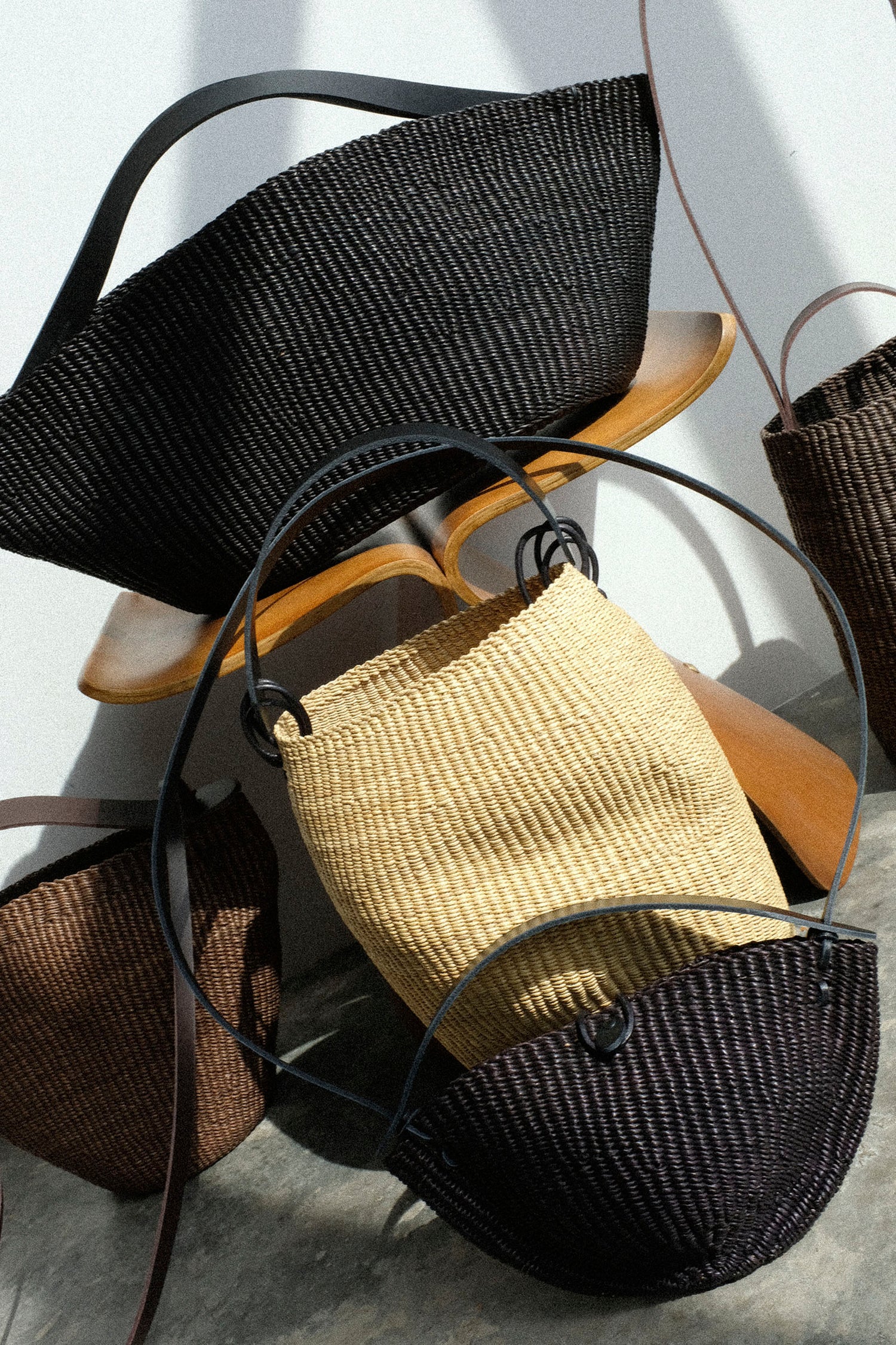 Woven bags made by Ines Bressand in black, brown, and beige on a light background