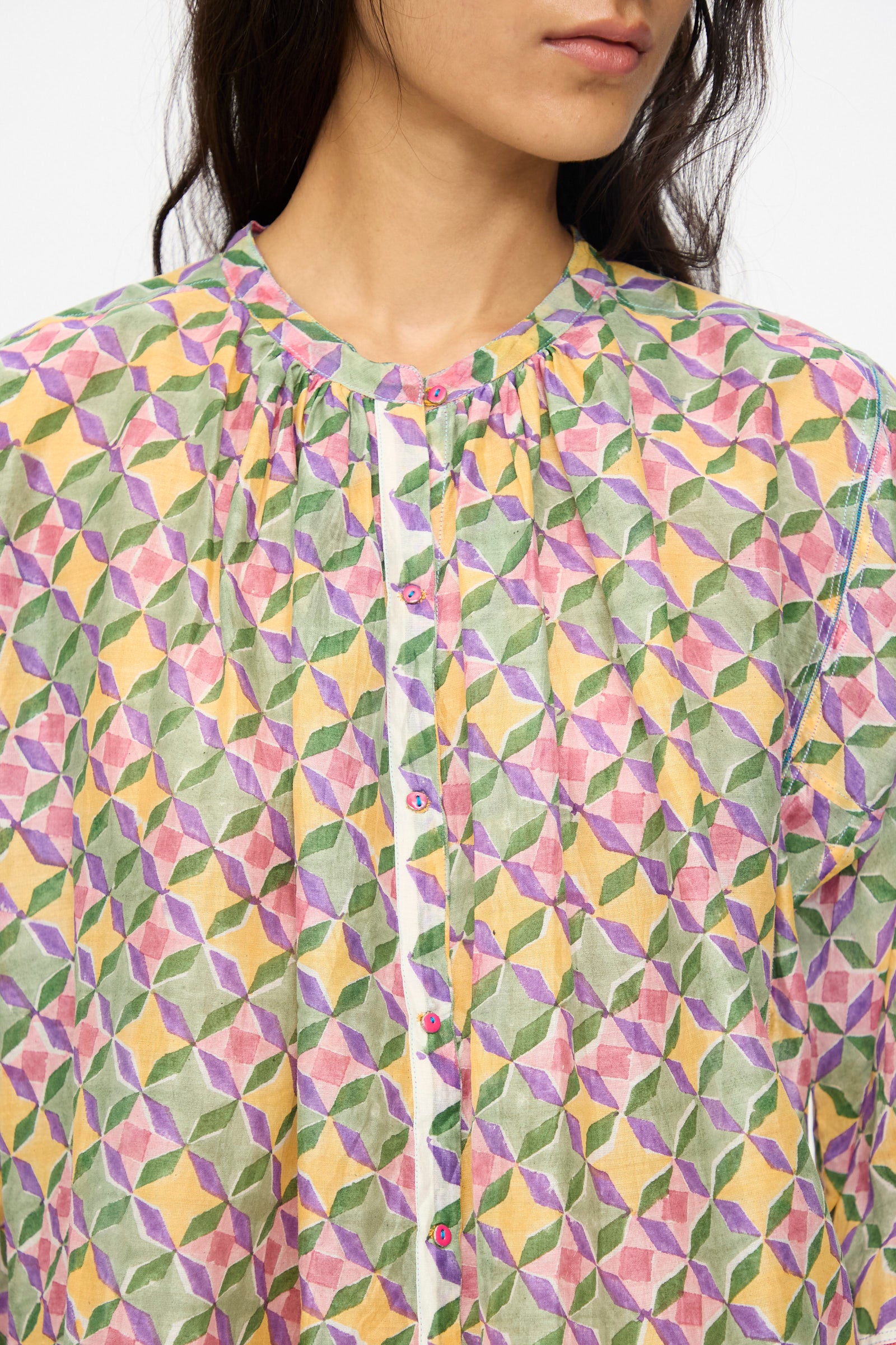A person wearing the Injiri Blockprint Chanderi Oliver Shirt in Multi, featuring a colorful geometric pattern in pink, green, yellow, and white.
