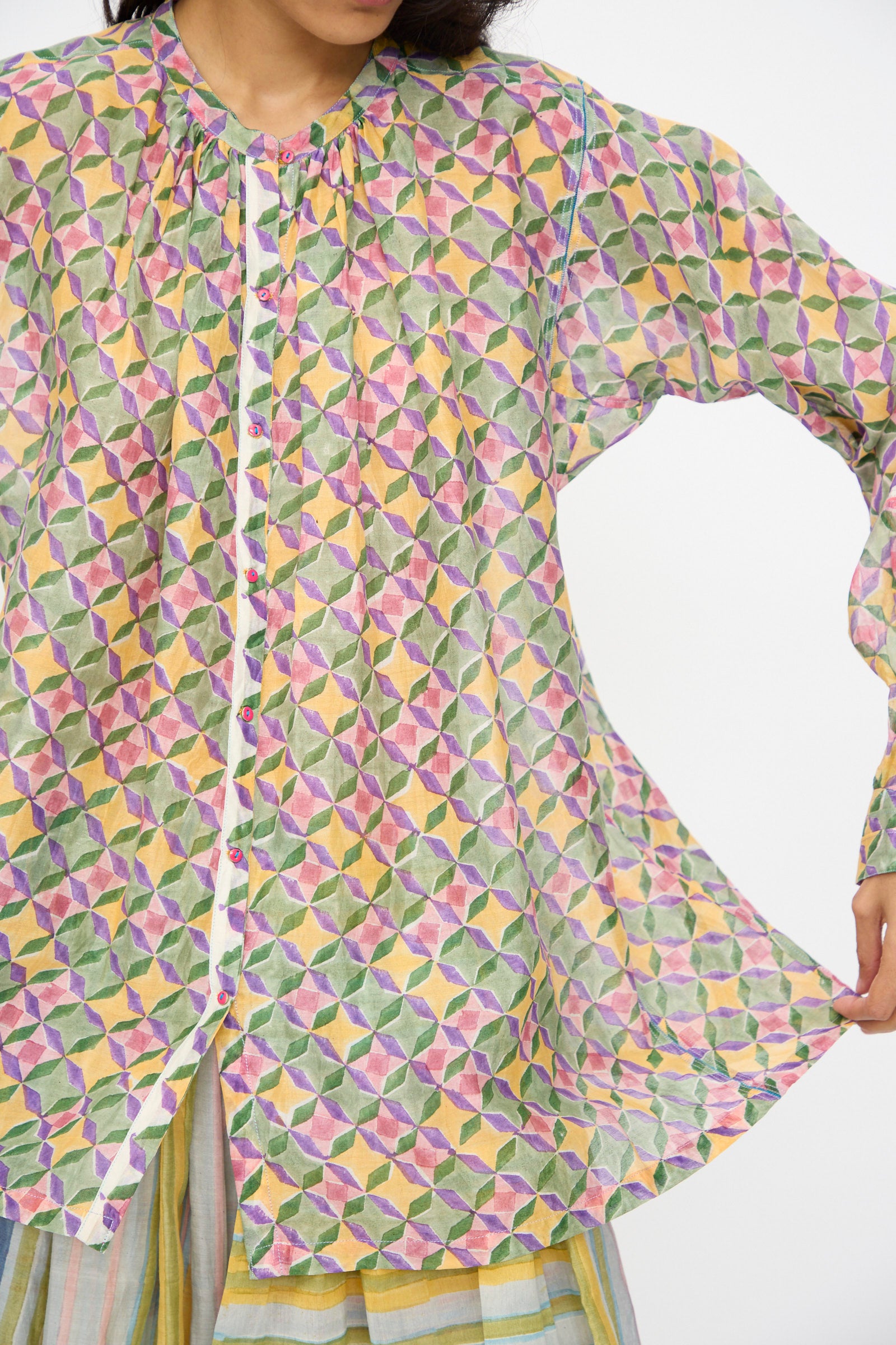 A person wears the Injiri Blockprint Chanderi Oliver Shirt in Multi, featuring vibrant geometric patterns, paired with striped pants.