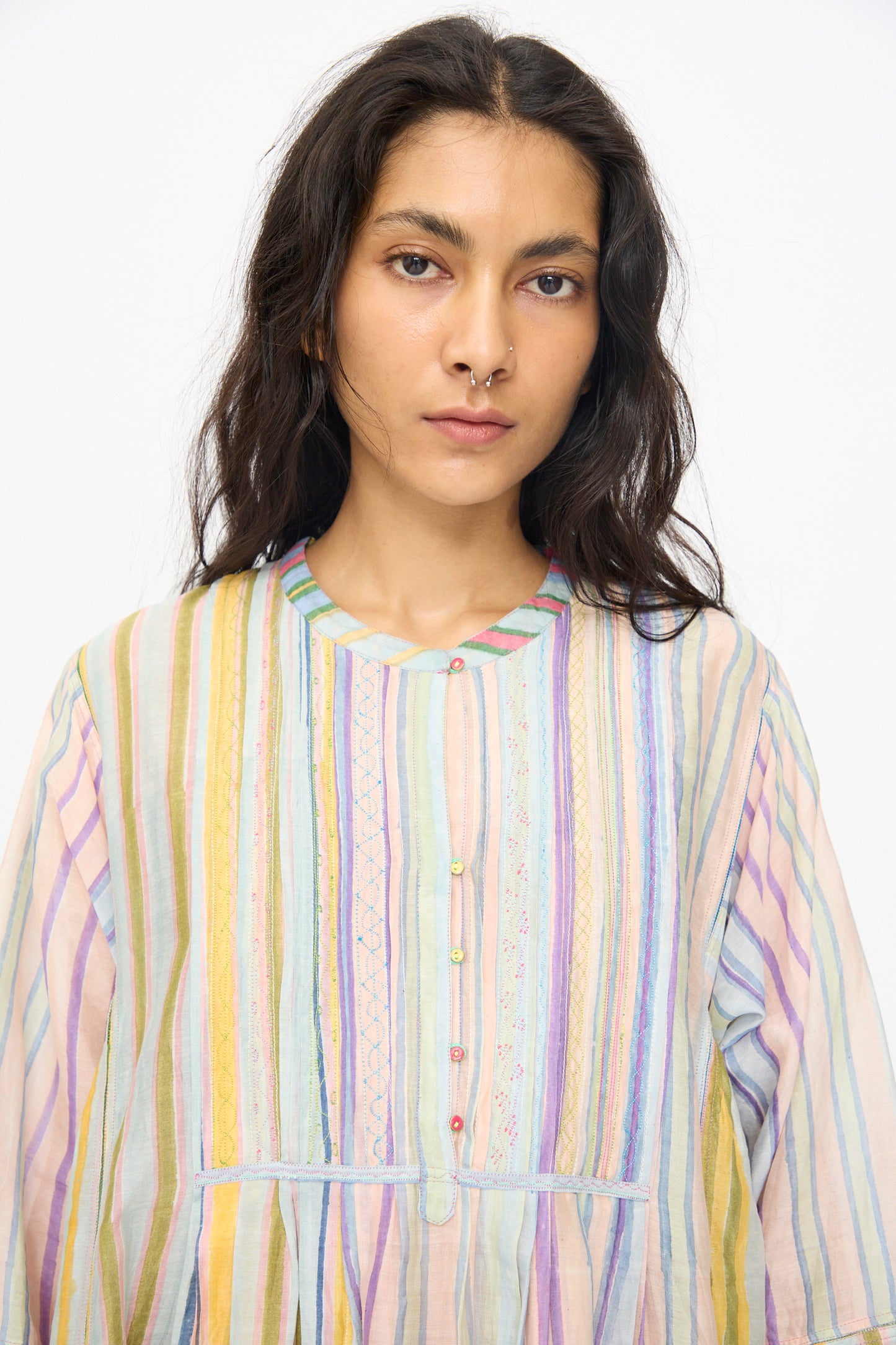 A person with long dark hair and a nose ring wears the Injiri Blockprint Chanderi Trumpet Dress in Multi Stripe, looking directly at the camera against a plain background.