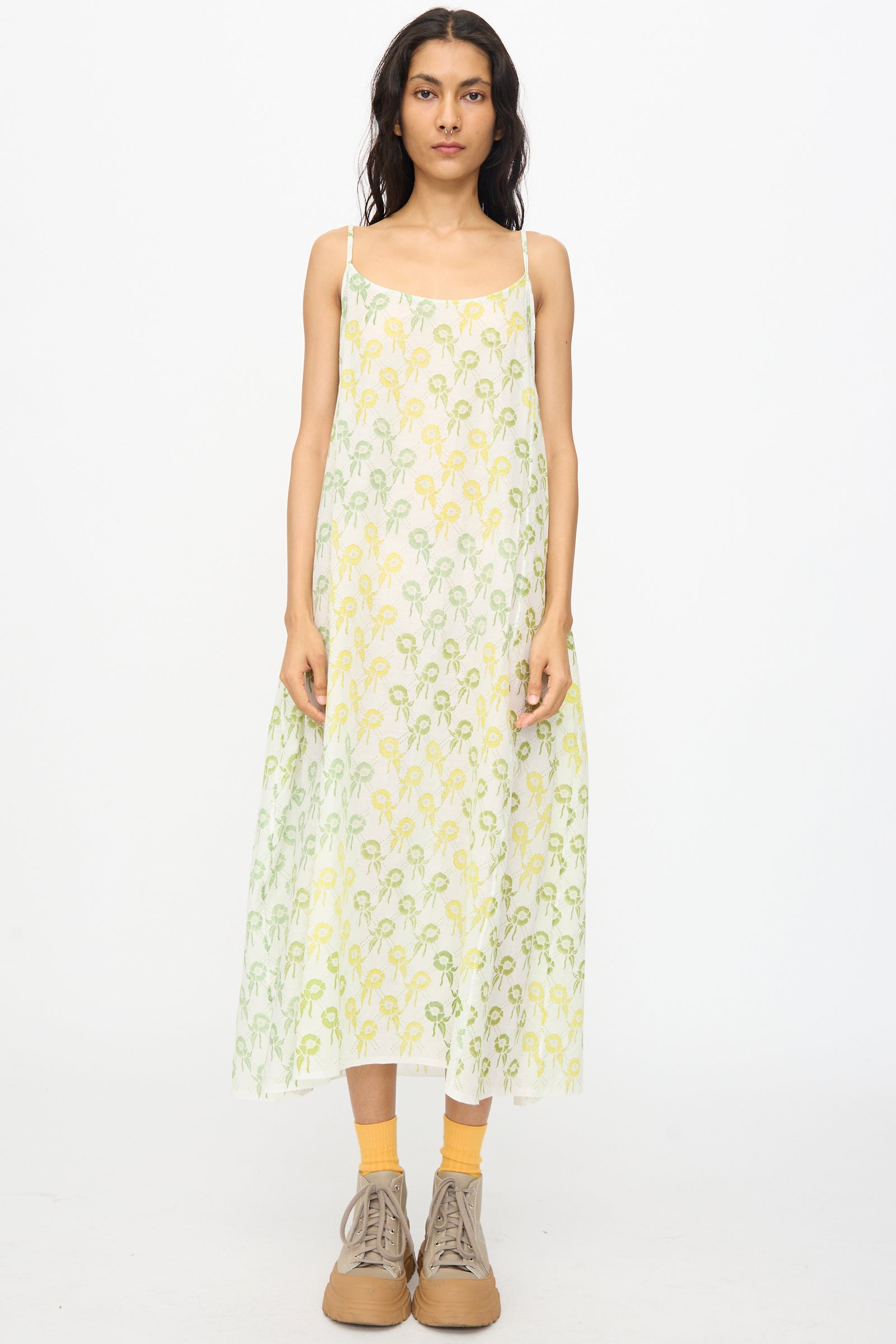 A person wears the Injiri Blockprint Cotton Emma Slip in Green Multi, paired with yellow socks and tan lace-up shoes, standing against a plain white background.