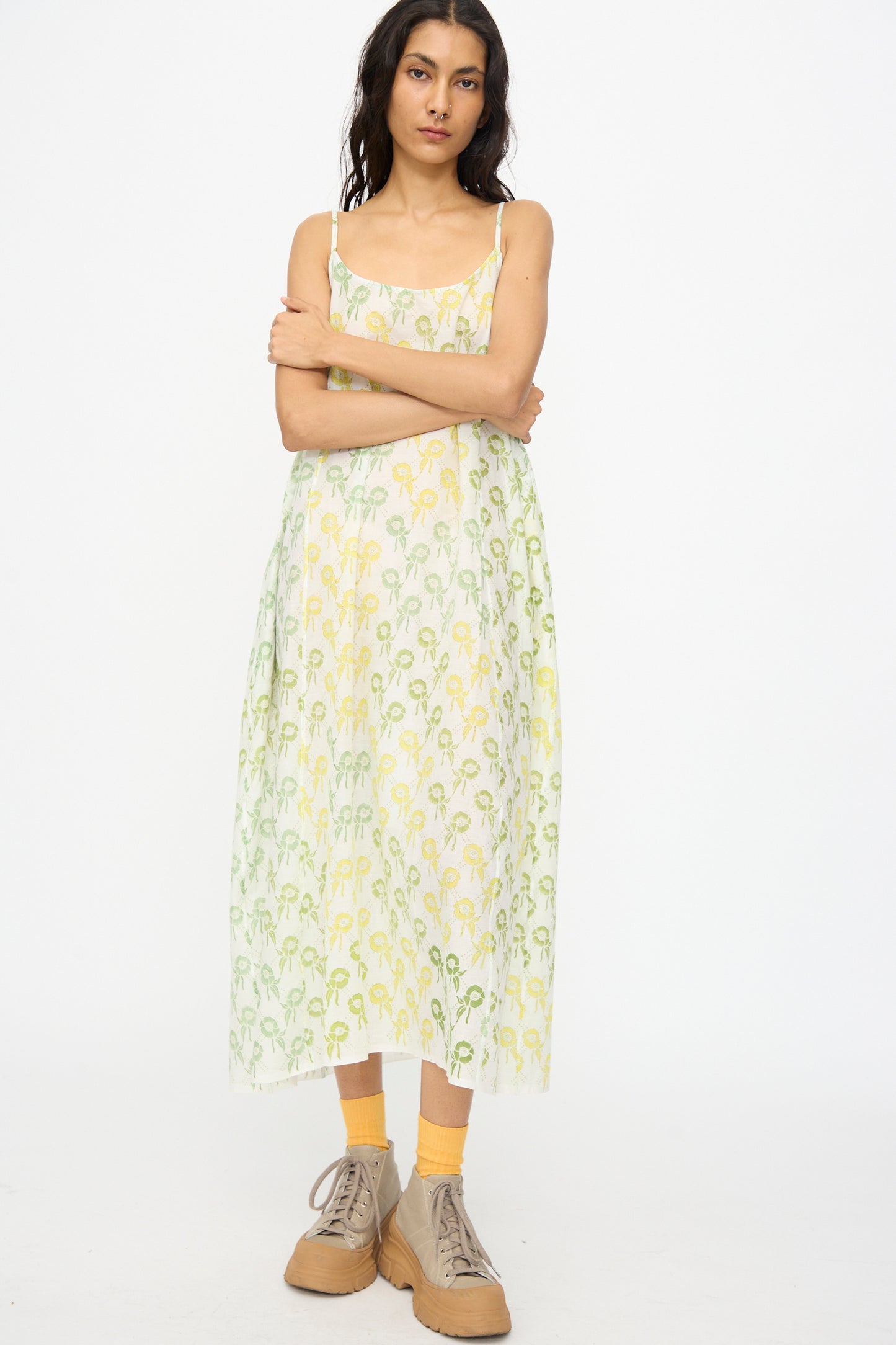 Woman standing with arms crossed, wearing the Injiri Blockprint Cotton Emma Slip in Green Multi, paired with yellow socks and beige shoes, against a plain white background.