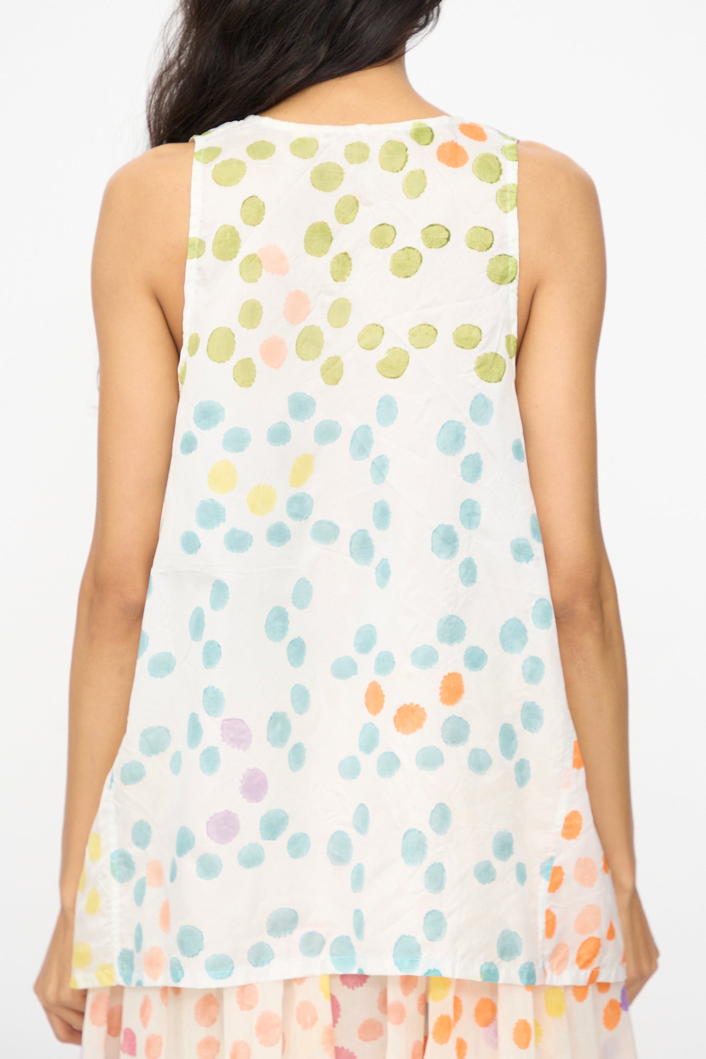 A woman is seen from behind wearing Injiri’s Blockprint Silk Bandi Top in White Multi, a sleeveless silk piece with colorful dots in green, orange, blue, and purple.