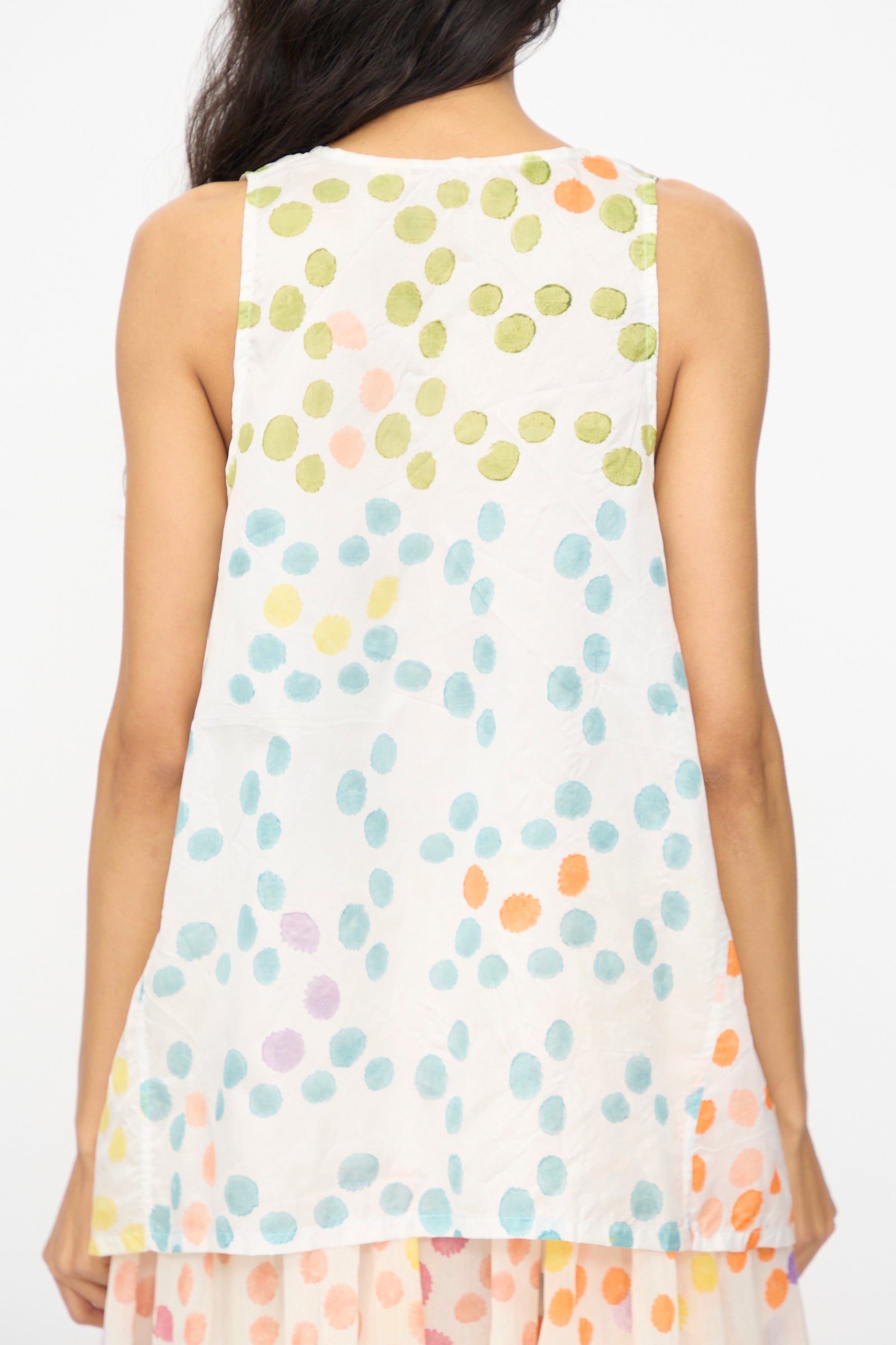 A woman is seen from behind wearing Injiri’s Blockprint Silk Bandi Top in White Multi, a sleeveless silk piece with colorful dots in green, orange, blue, and purple.