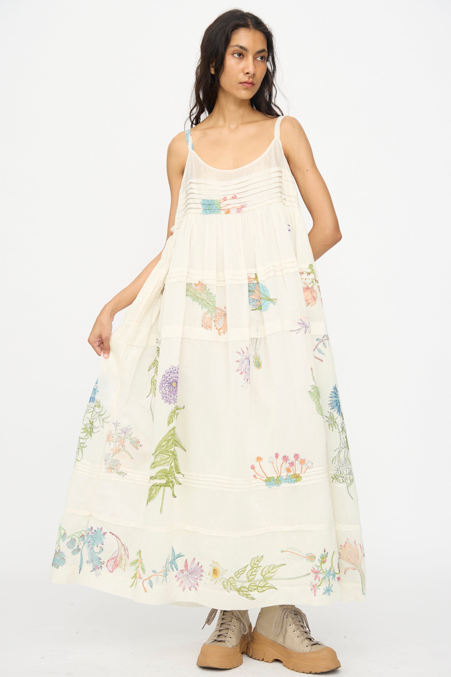 A woman wears the Injiri Cotton Silk Blockprint Hazel Slip in White Floral, paired with tan boots, standing against a plain white background.