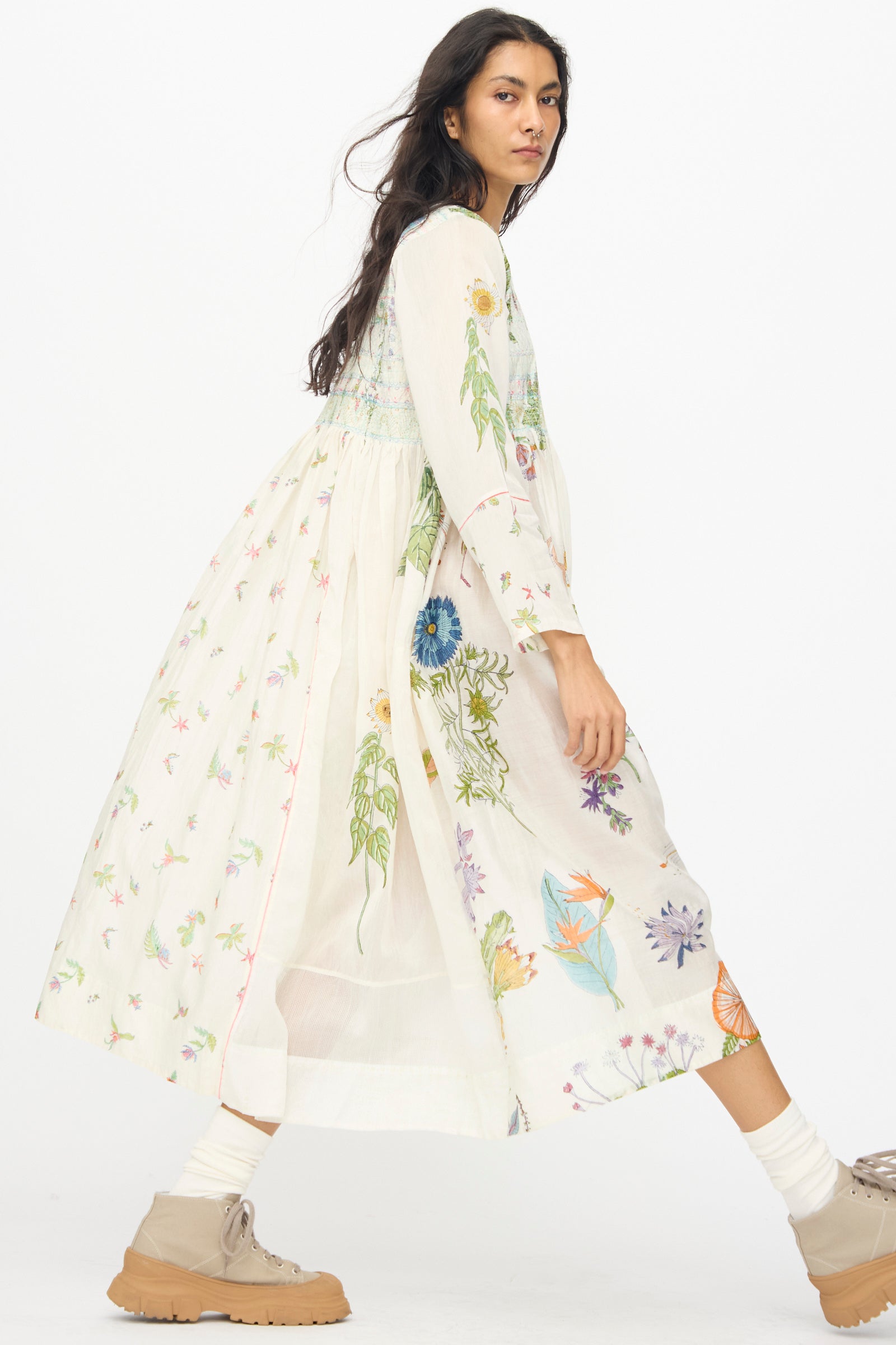 A person wears the Injiri Cotton Silk Blockprint Nazma Dress in White, paired with cream socks and tan shoes, standing against a plain white background.