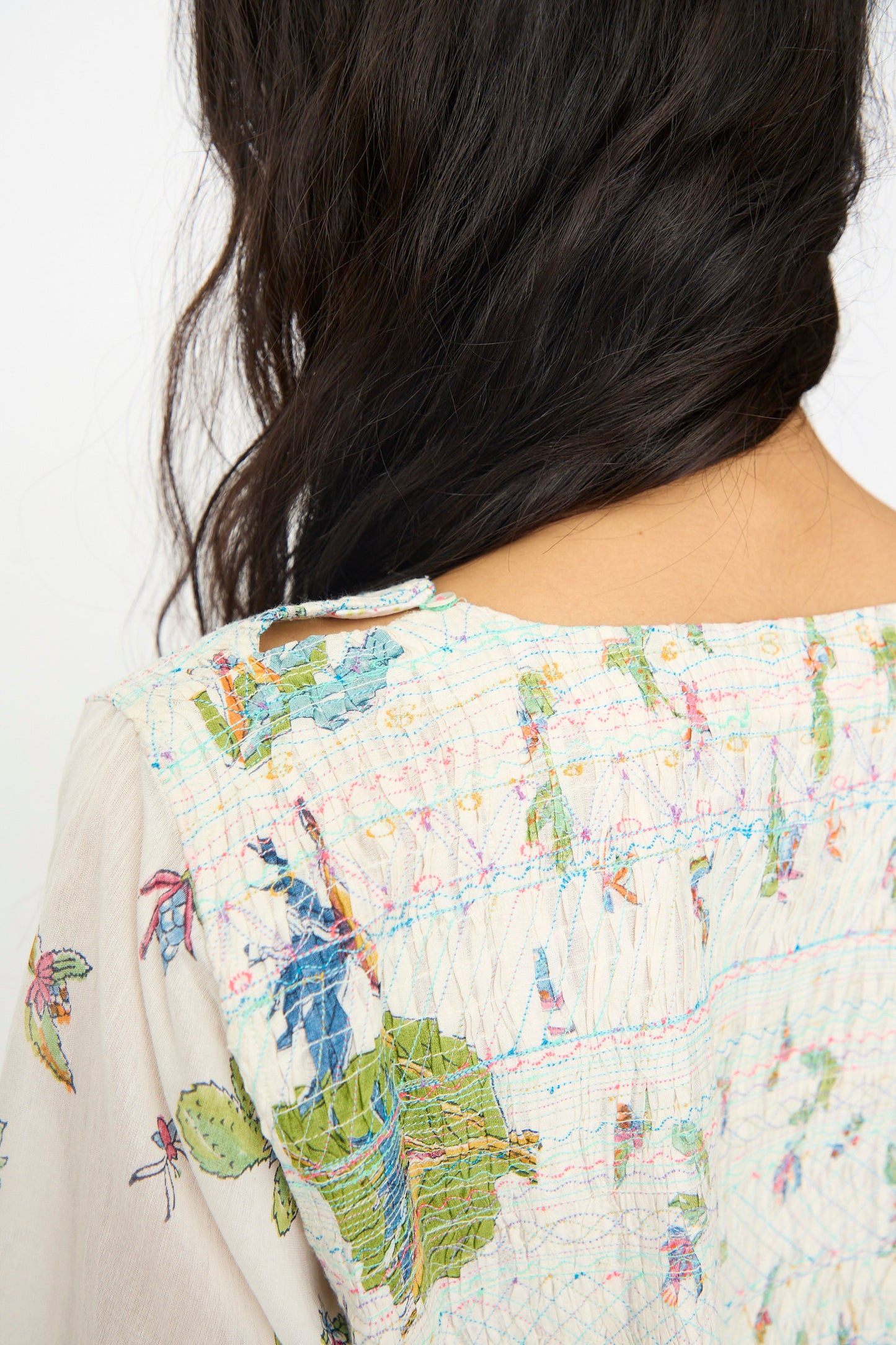 The back view shows a woman with long, dark, wavy hair wearing the Injiri Cotton Silk Blockprint Nazma Dress in White, featuring colorful floral and leaf patterns inspired by traditional Chanderi designs.