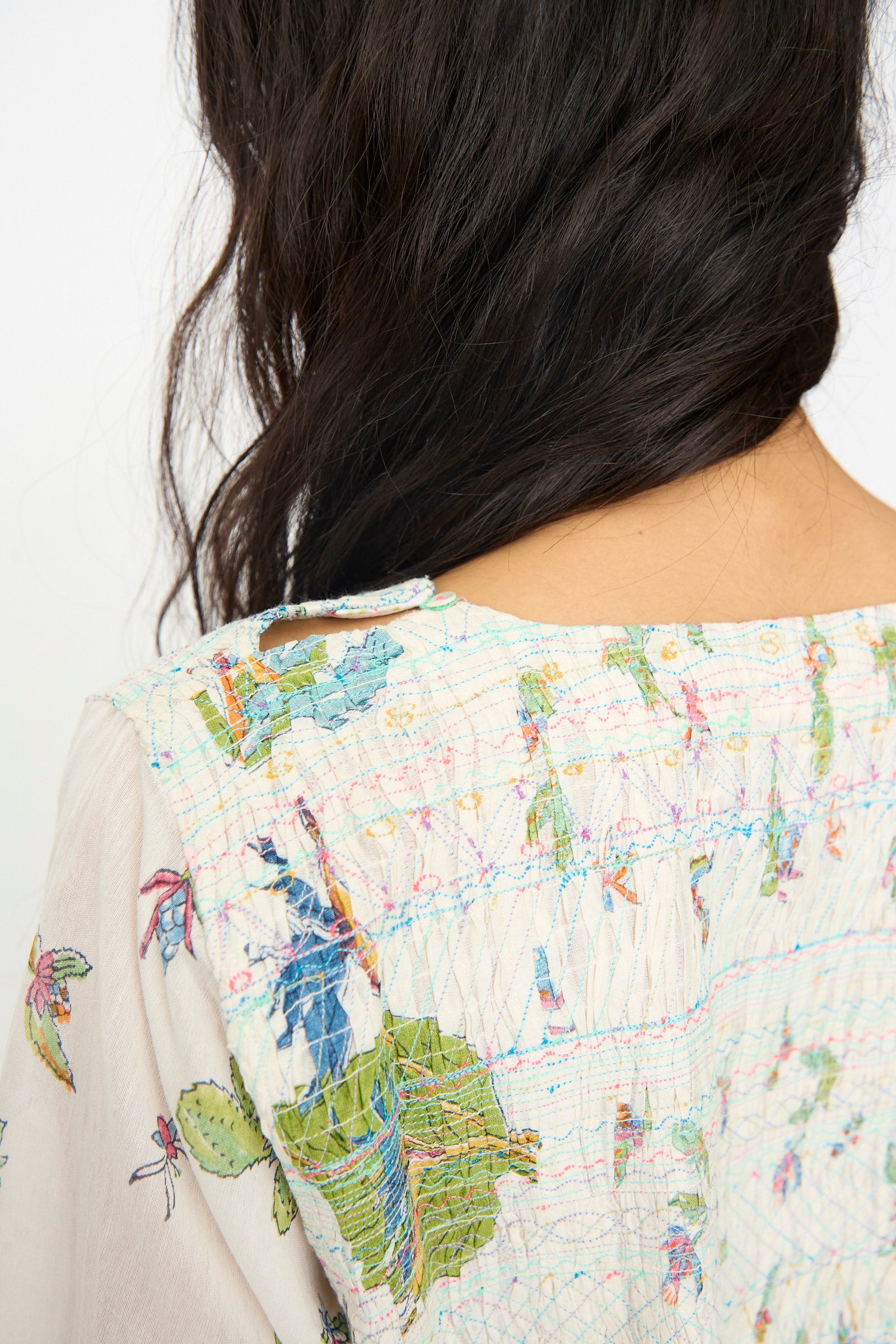 The back view shows a woman with long, dark, wavy hair wearing the Injiri Cotton Silk Blockprint Nazma Dress in White, featuring colorful floral and leaf patterns inspired by traditional Chanderi designs.