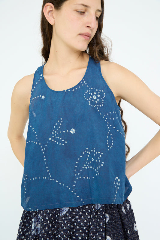 A woman with long hair wears the Injiri Cotton Tank in Blue, featuring a floral pattern, paired with a patterned skirt.