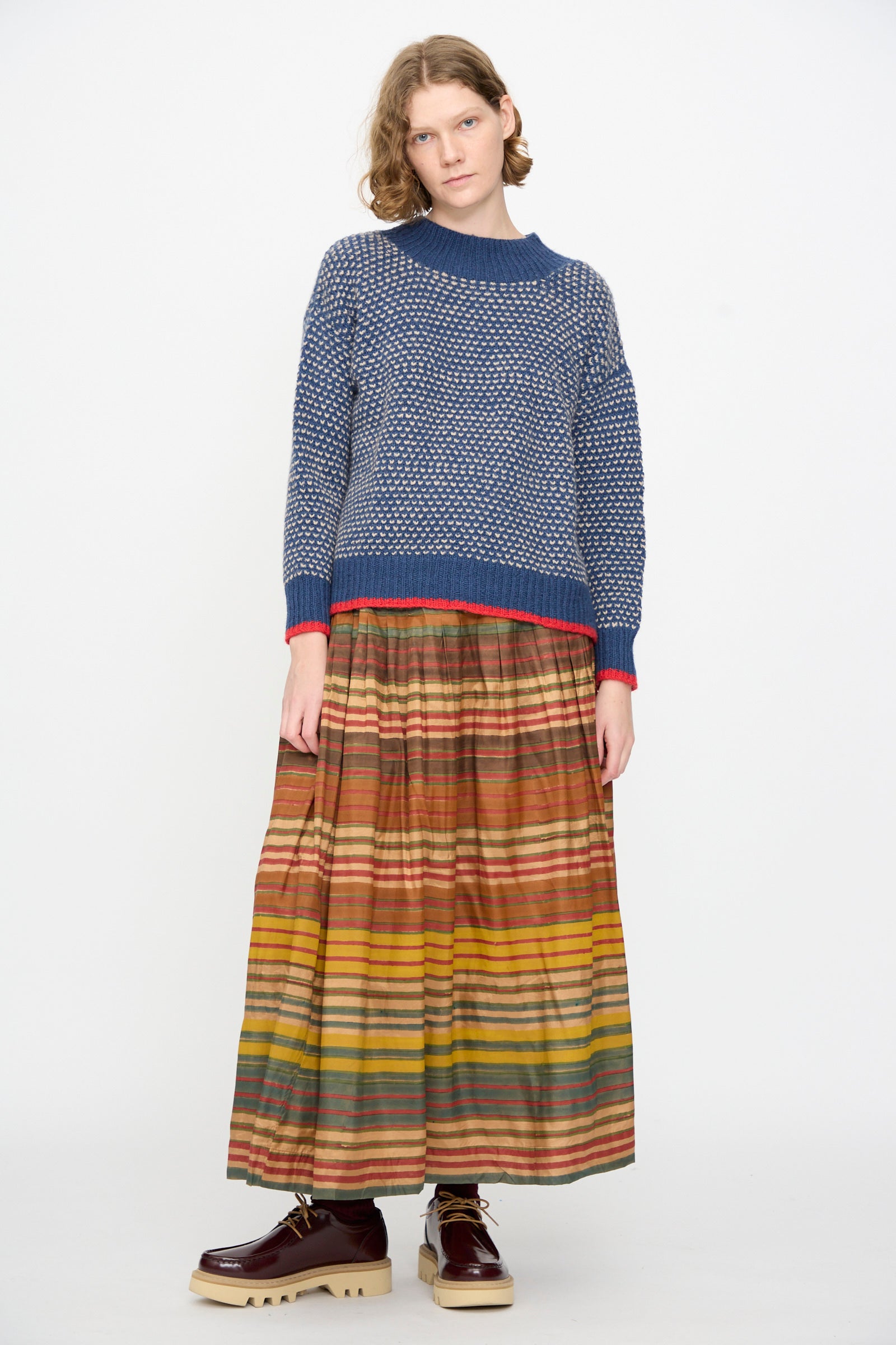 A person stands against a white background, wearing the Injiri Knitted Wool Sweater in Blue.